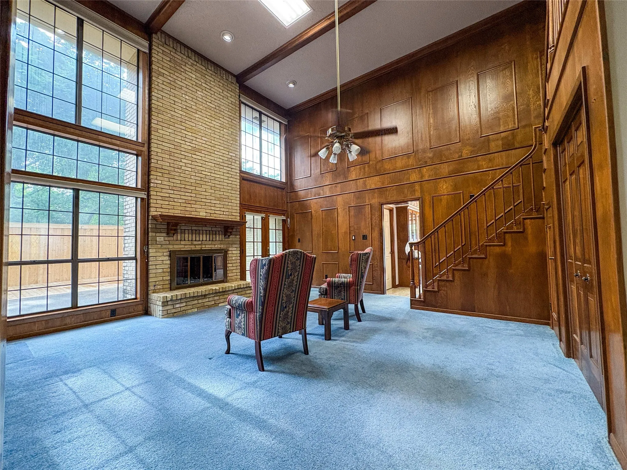 ADDITIONAL VIEW OF LIVING ROOM WITH THE RICH WOOD TONES AND TALL WINDOWS