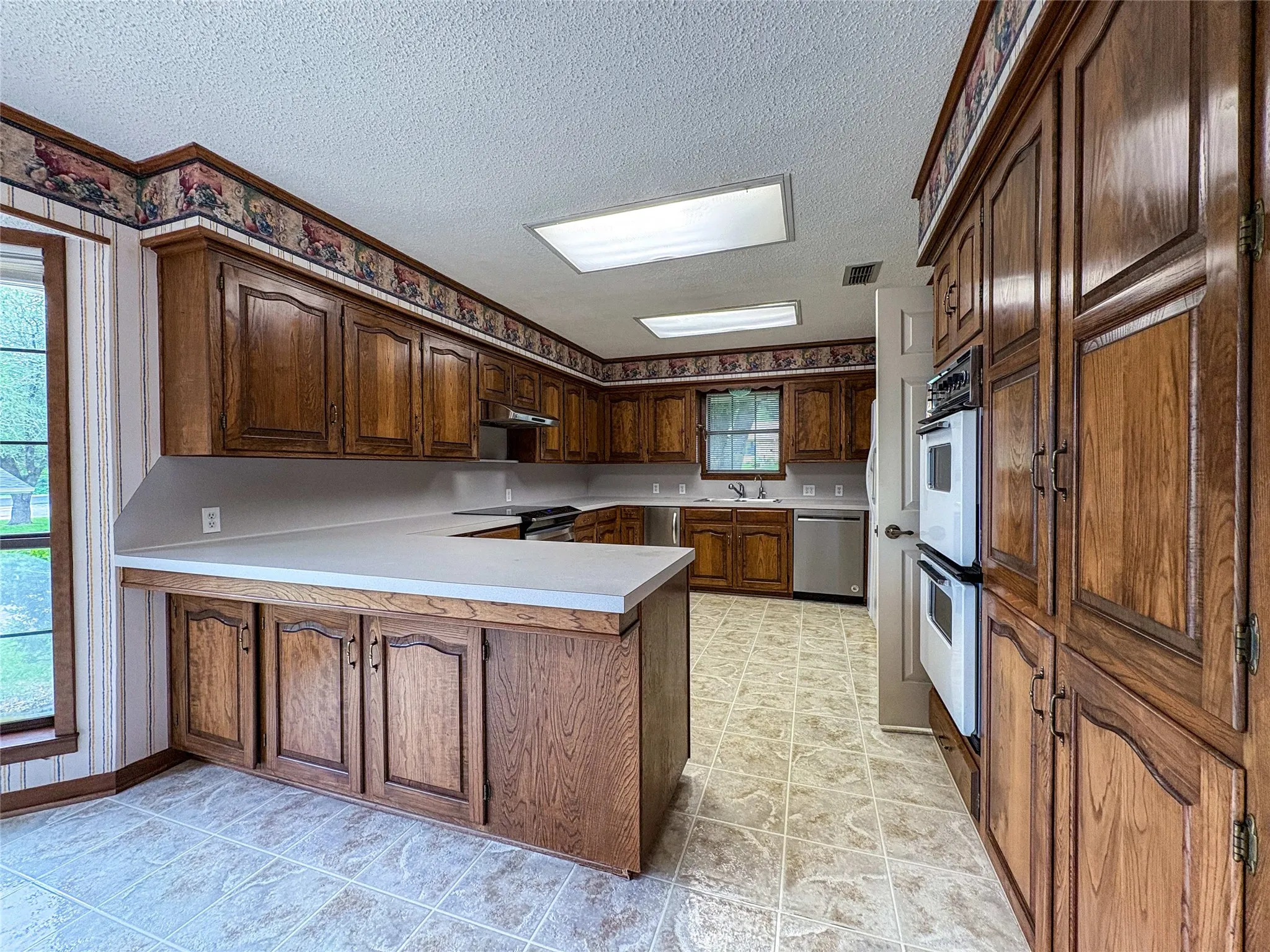 LARGE OPEN KITCHEN WITH A BREAKFAST BAR, RANGE AND DOUBLE OVENS