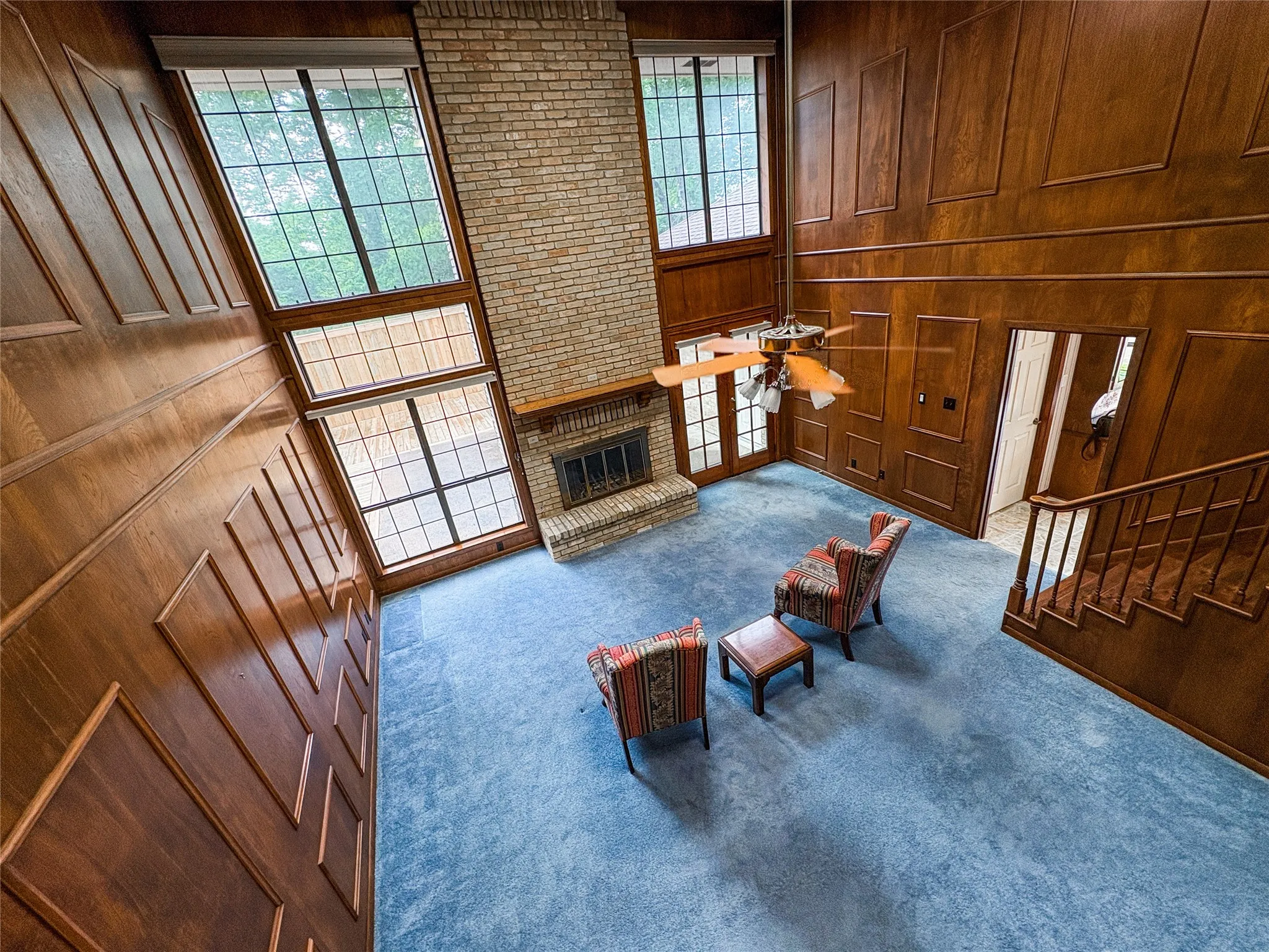 UPSTAIR VIEW OF THE LIVING ROOM WITH FIREPLACE AND LTALL WINDOWS