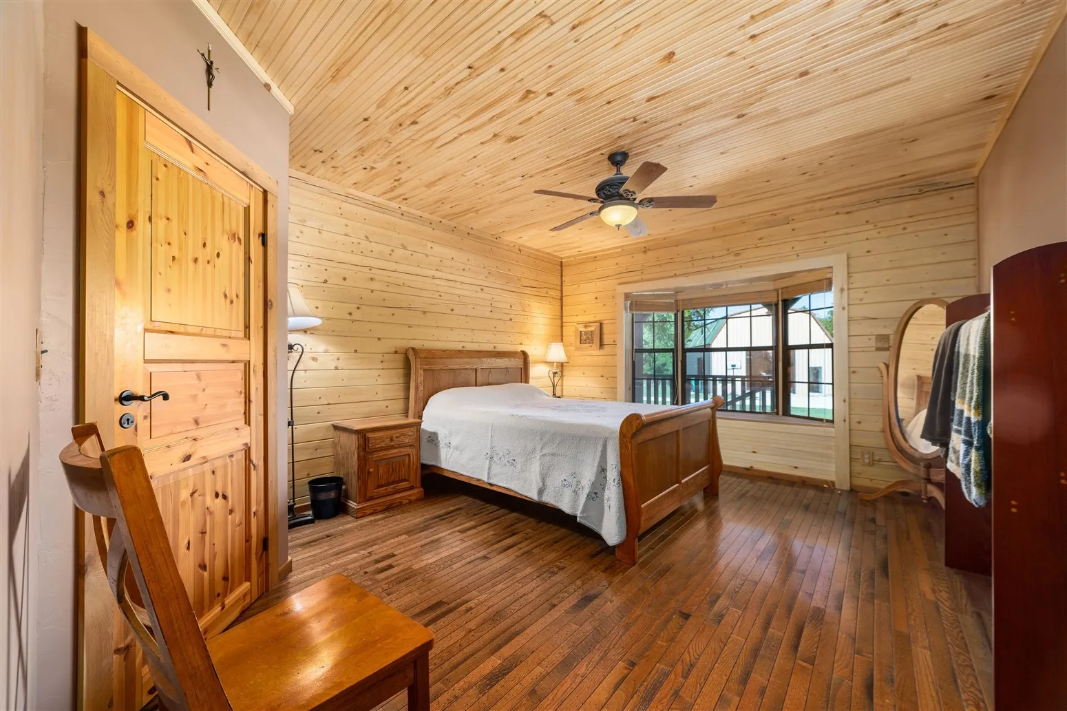 Bedroom with wood ceiling, wood walls, a ceiling fan, and dark wood-style floors