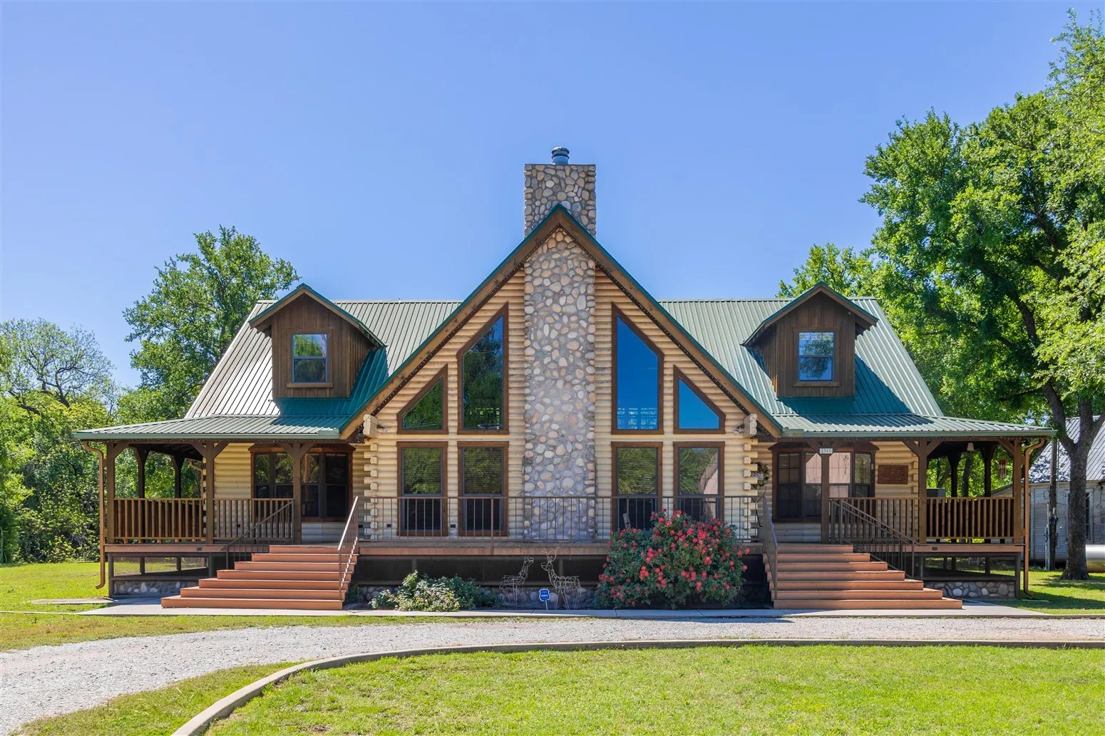View of front facade with a chimney, covered porch, and log siding