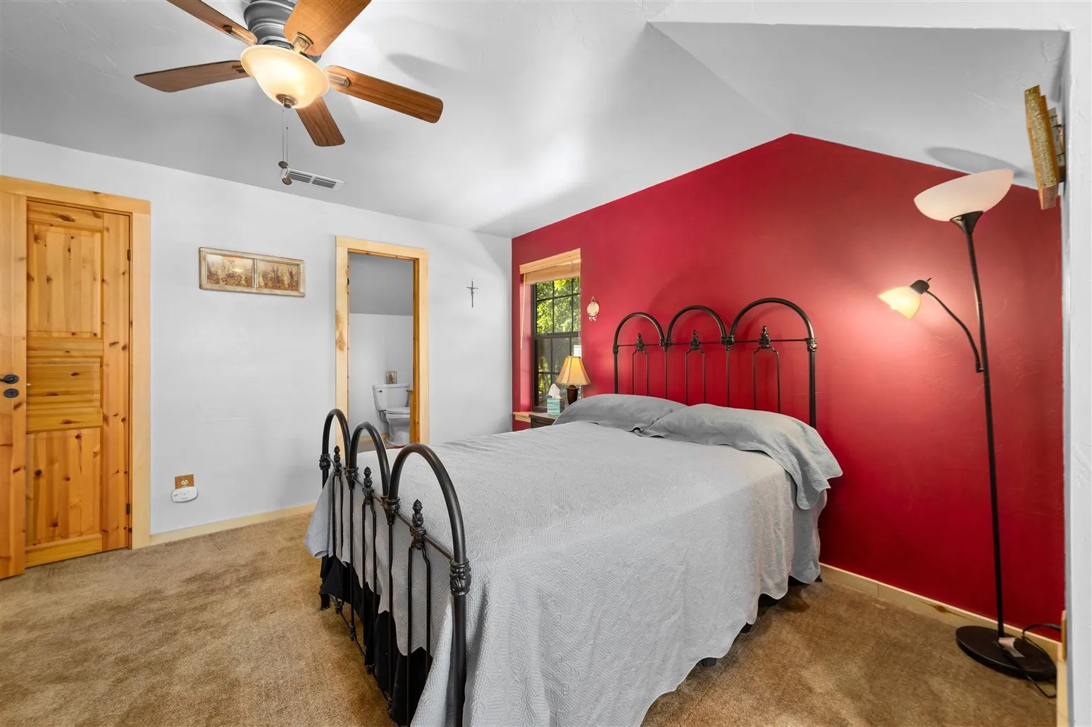 Bedroom with carpet flooring, ensuite bathroom, visible vents, lofted ceiling, and ceiling fan