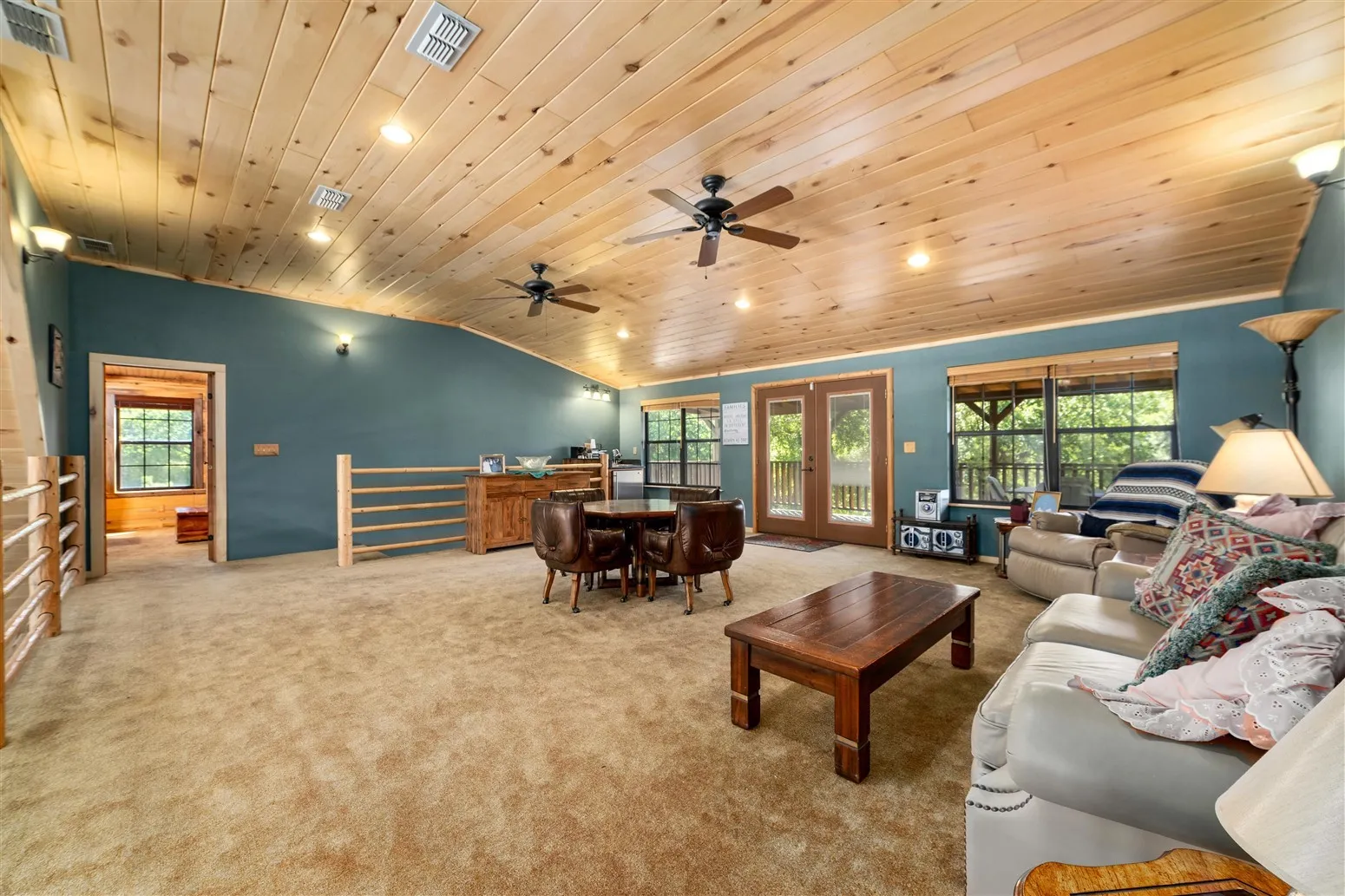 Carpeted living room with wood ceiling, vaulted ceiling, visible vents, and plenty of natural light