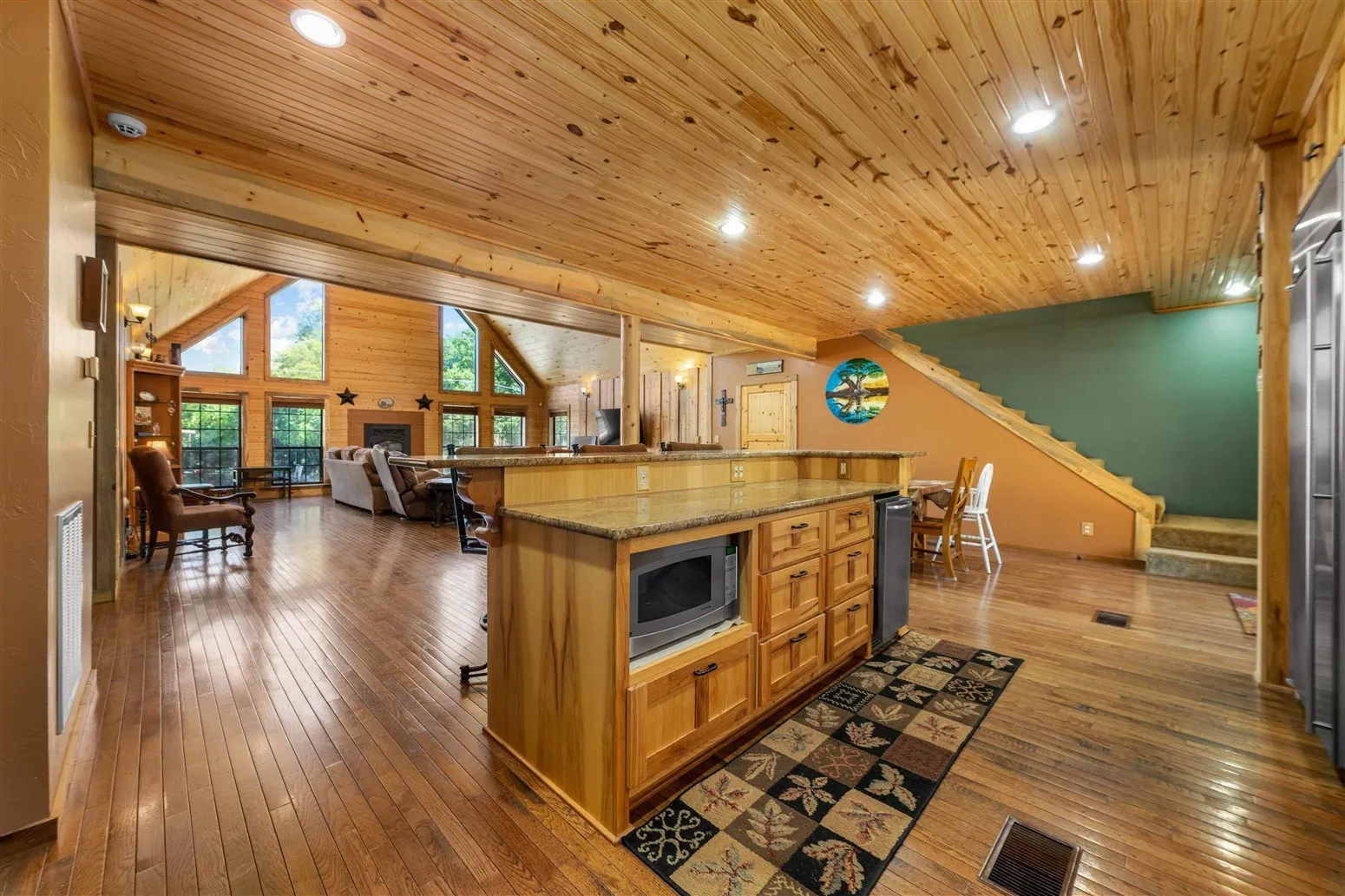 Kitchen featuring open floor plan, wooden ceiling, a kitchen bar, stainless steel microwave, and dark wood-style flooring