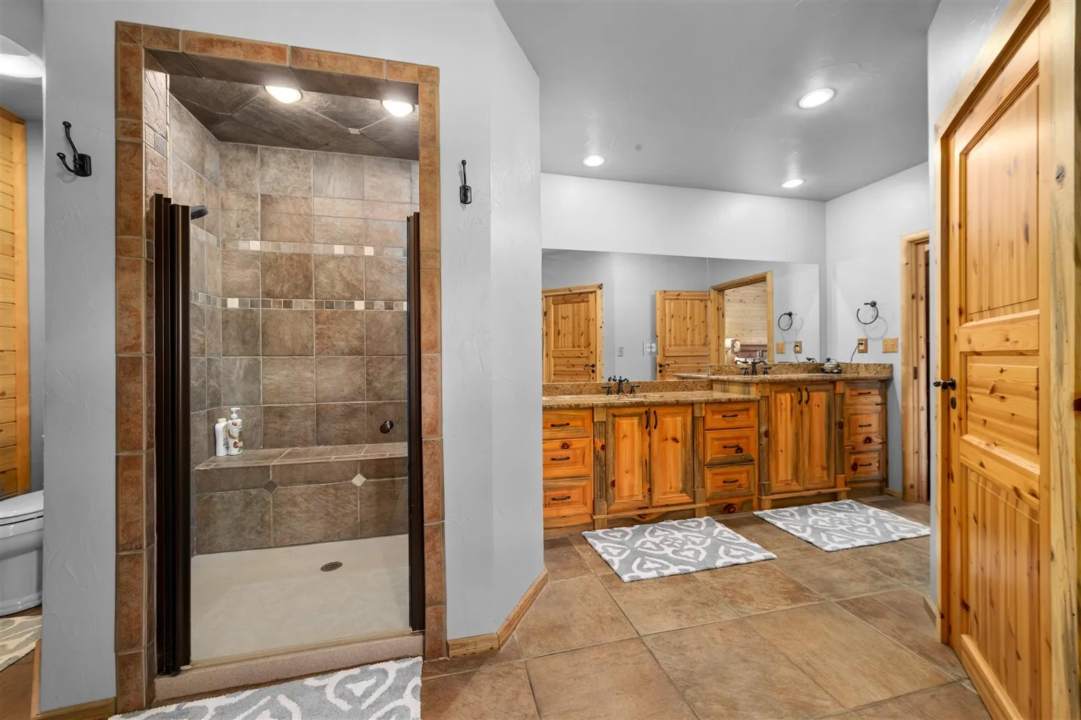 Full bathroom featuring toilet, a sink, a stall shower, double vanity, and baseboards