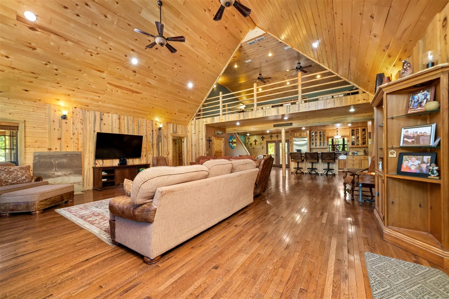 Living area featuring wood ceiling, wood walls, high vaulted ceiling, and ceiling fan