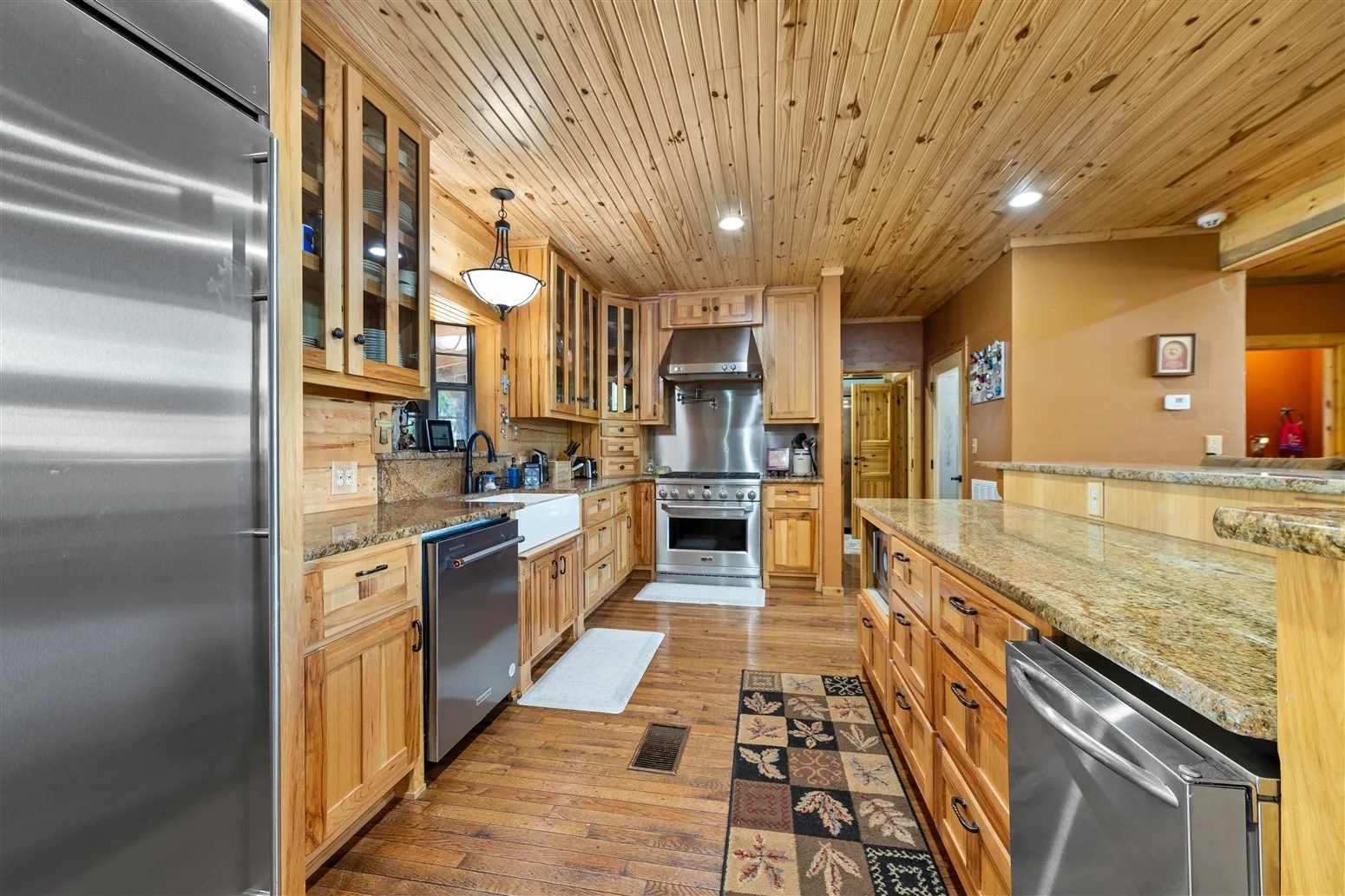 Kitchen featuring premium appliances, a sink, light wood-style flooring, under cabinet range hood, and recessed lighting