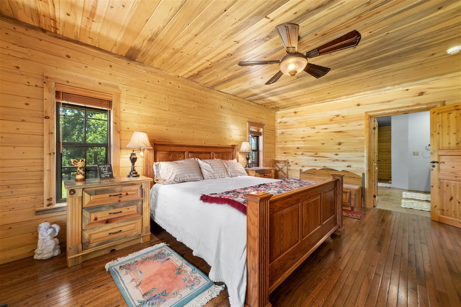 Bedroom with wood ceiling, wood walls, a ceiling fan, and dark wood-type flooring