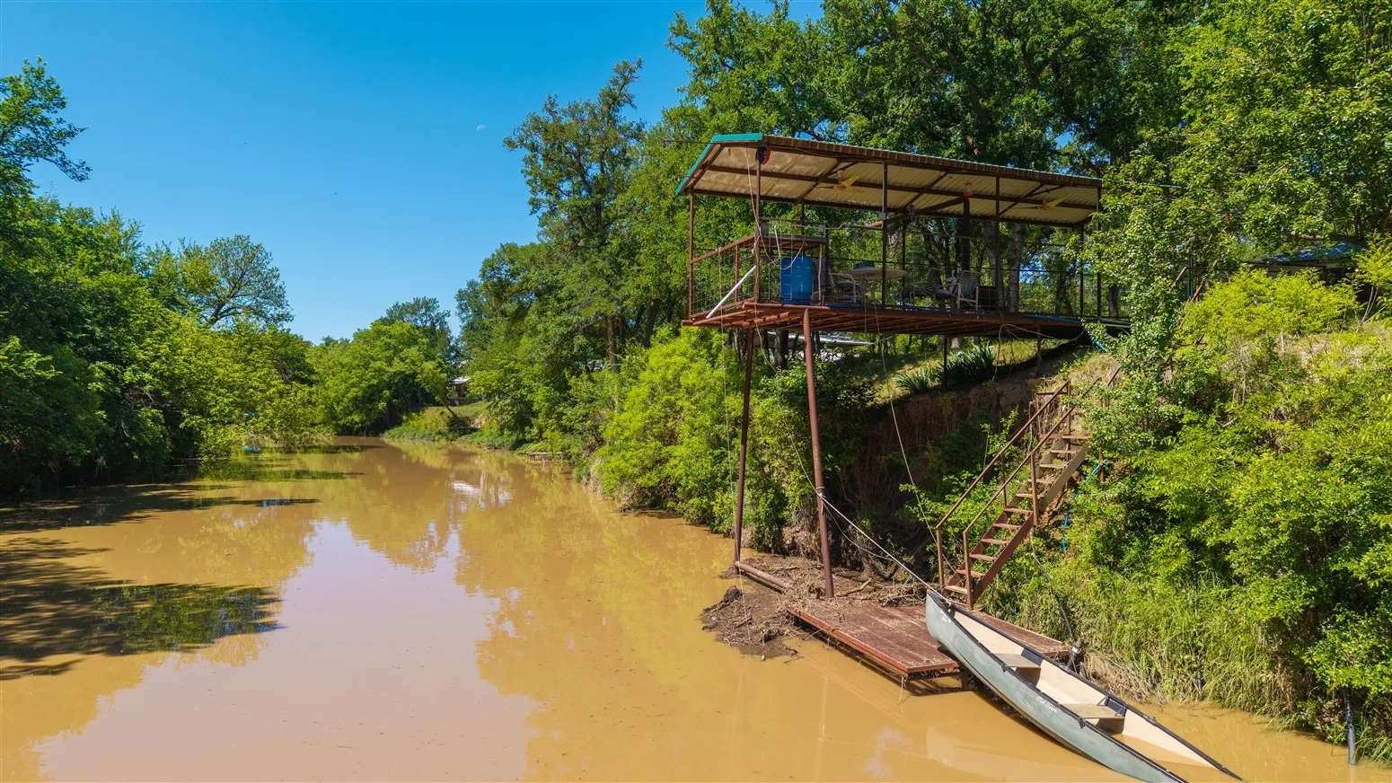 Water view with a floating dock and a wooded view