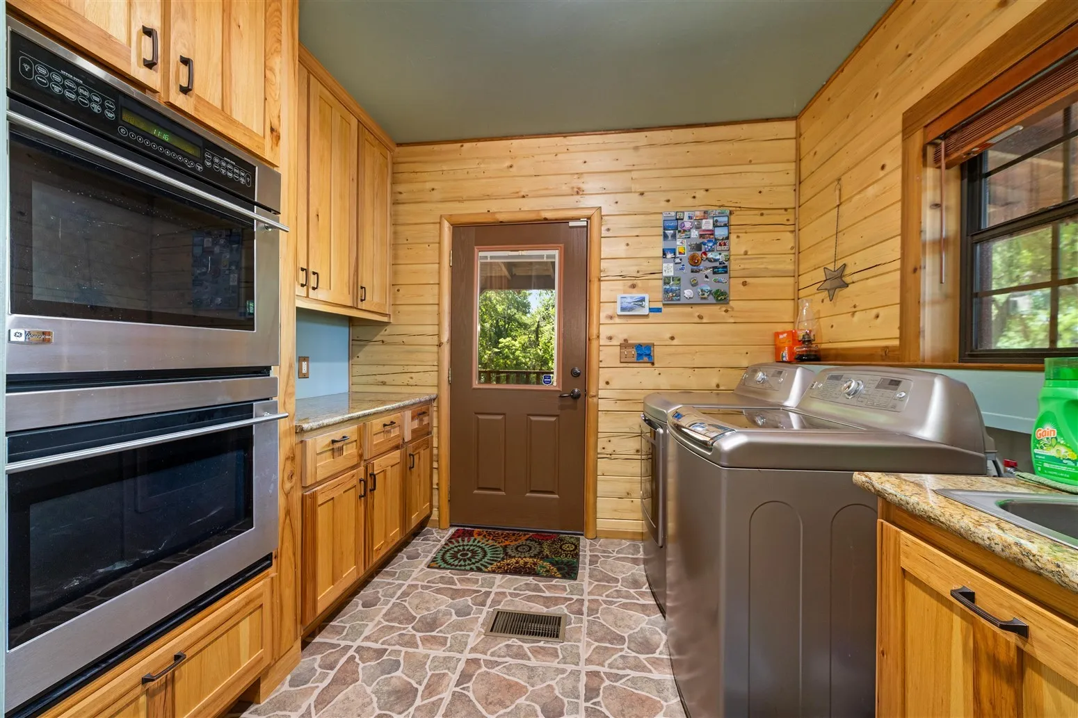 Clothes washing area with visible vents, stone finish floor, wooden walls, washer and dryer, and laundry area