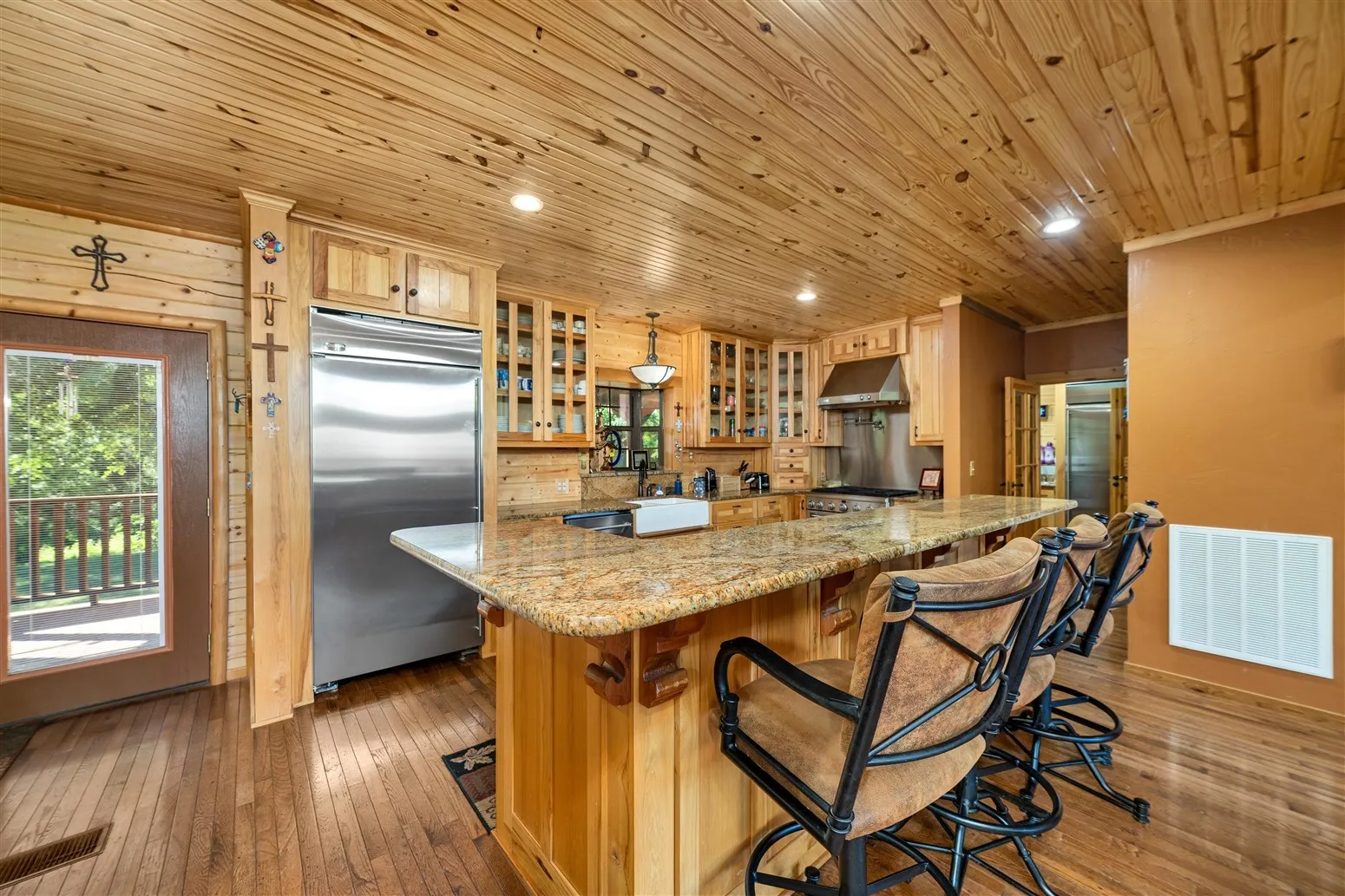 Kitchen with stainless steel appliances, hardwood / wood-style flooring, visible vents, extractor fan, and wooden ceiling