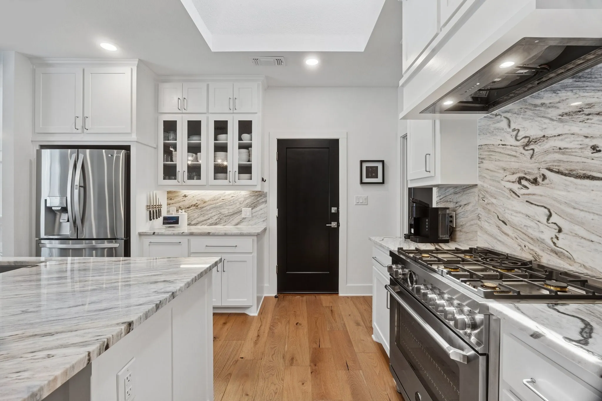 Kitchen featuring stainless steel appliances, wall chimney range hood, decorative backsplash, white cabinetry, and recessed lighting