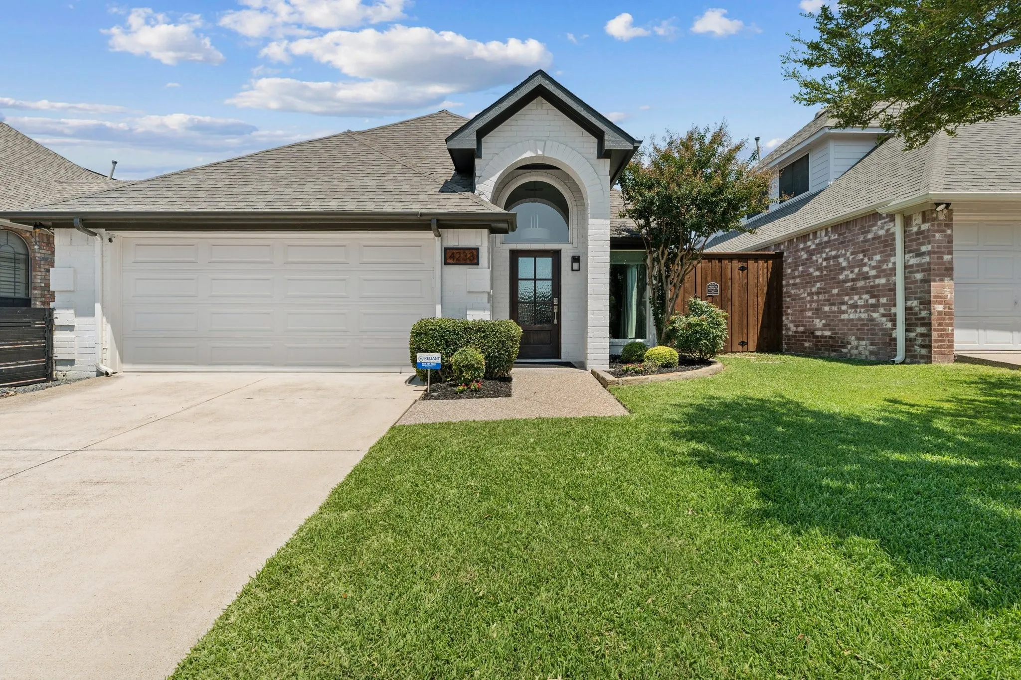 View of front of house featuring roof with shingles, a garage, concrete driveway, brick siding, and a front yard