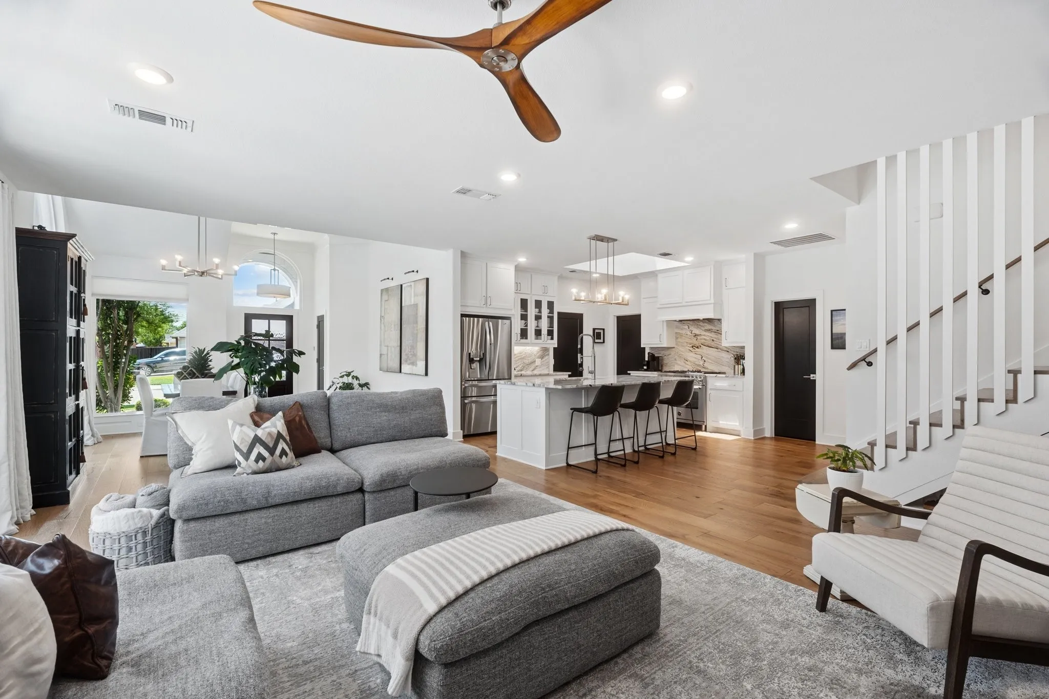 Living room with a chandelier, light wood-style flooring, a ceiling fan, stairway, and recessed lighting
