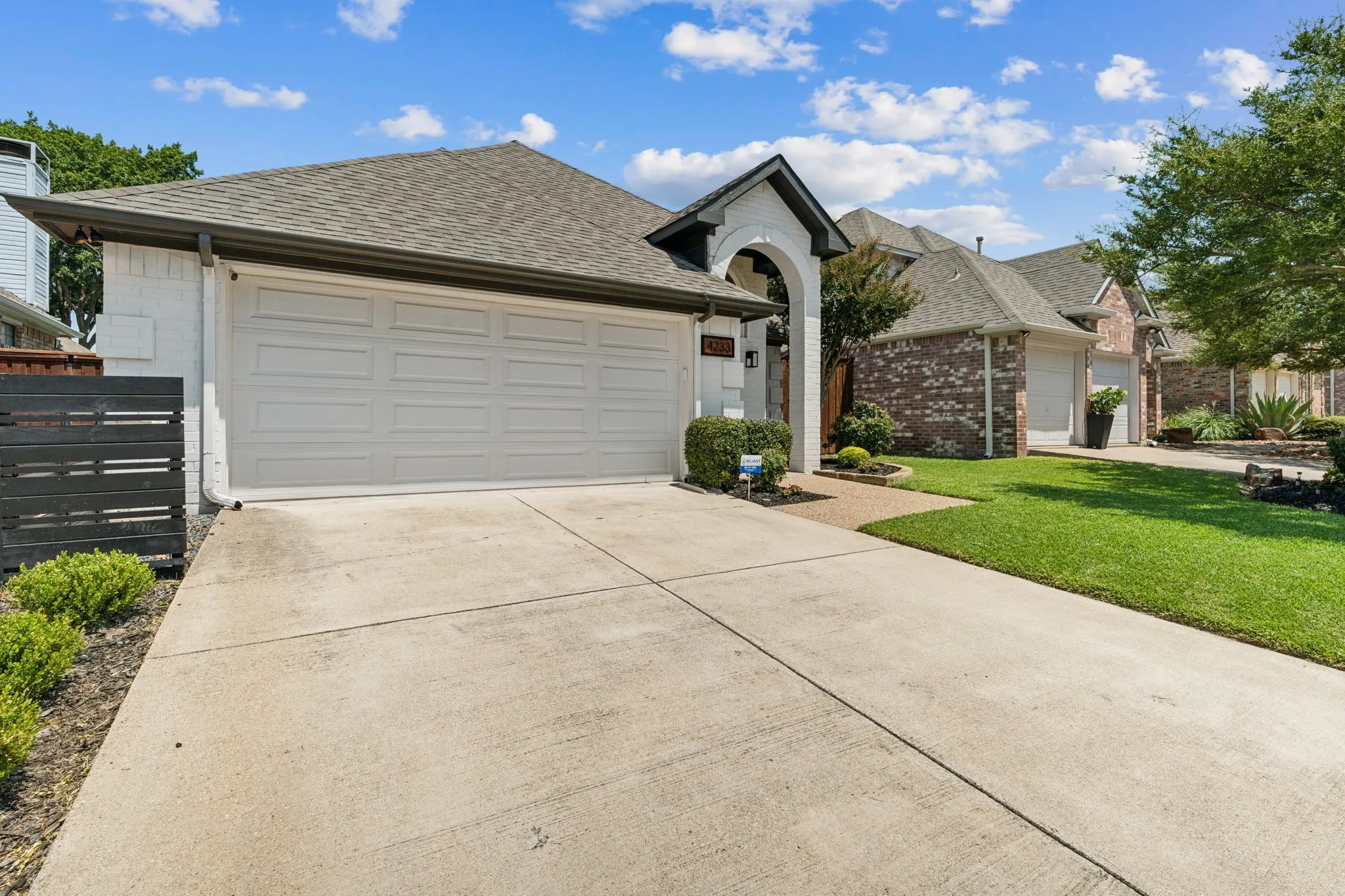Single story home with a shingled roof, concrete driveway, an attached garage, and brick siding