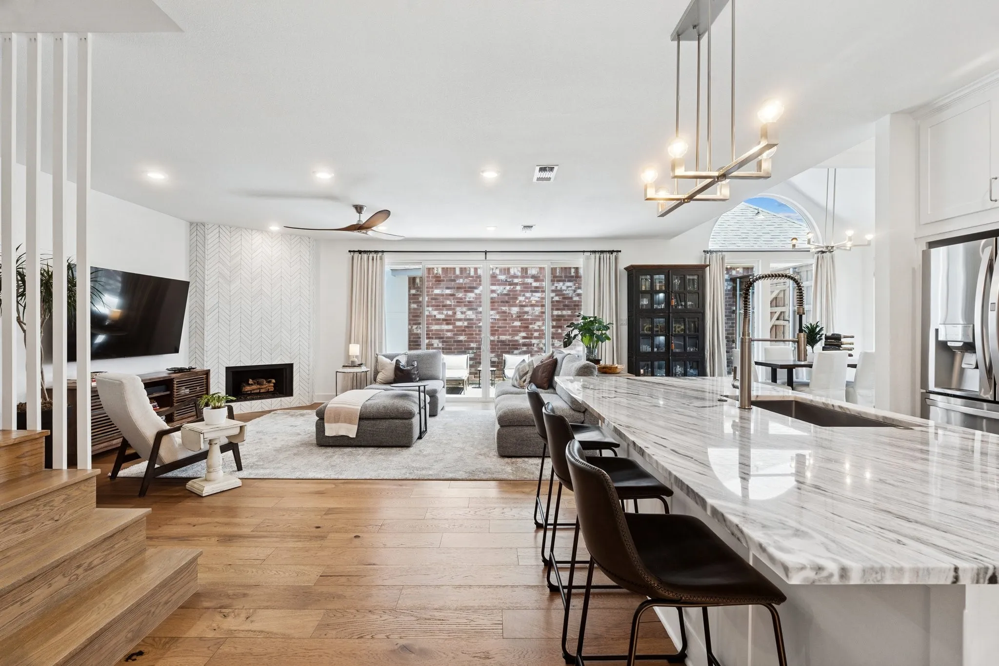 Kitchen with light wood finished floors, open floor plan, light stone counters, white cabinetry, and stainless steel fridge