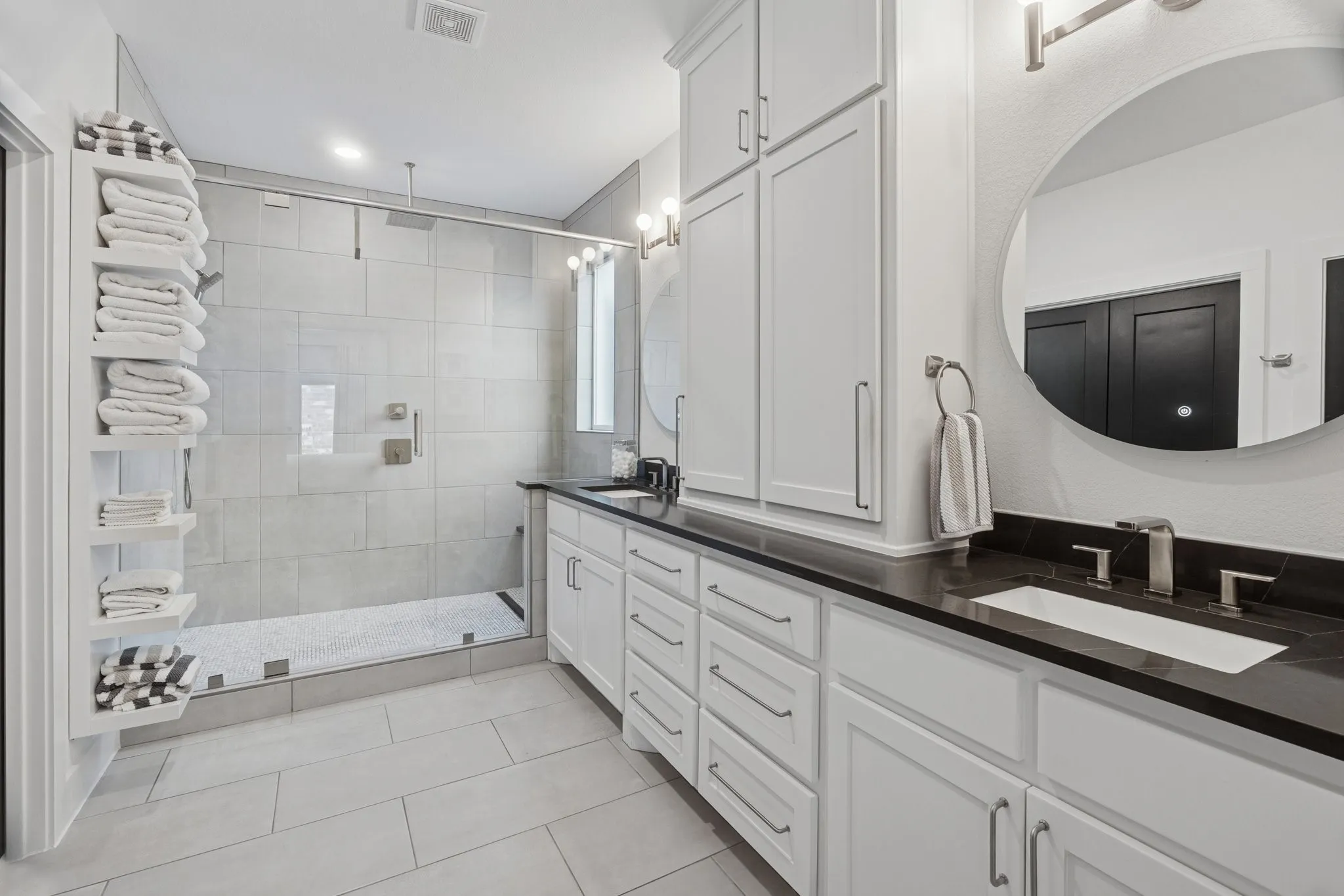 Full bath with double vanity, a shower stall, and tile patterned floors
