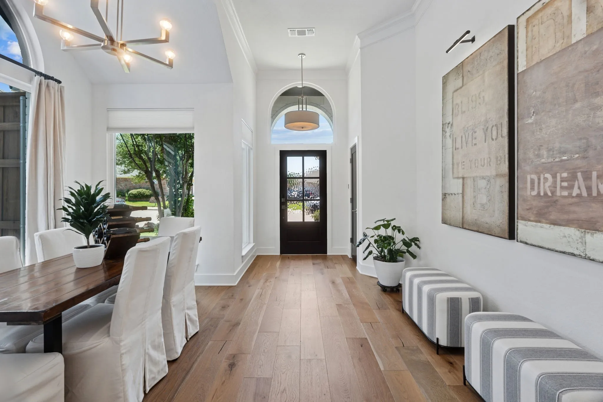 Entryway featuring wood-type flooring, a chandelier, ornamental molding, and a high ceiling