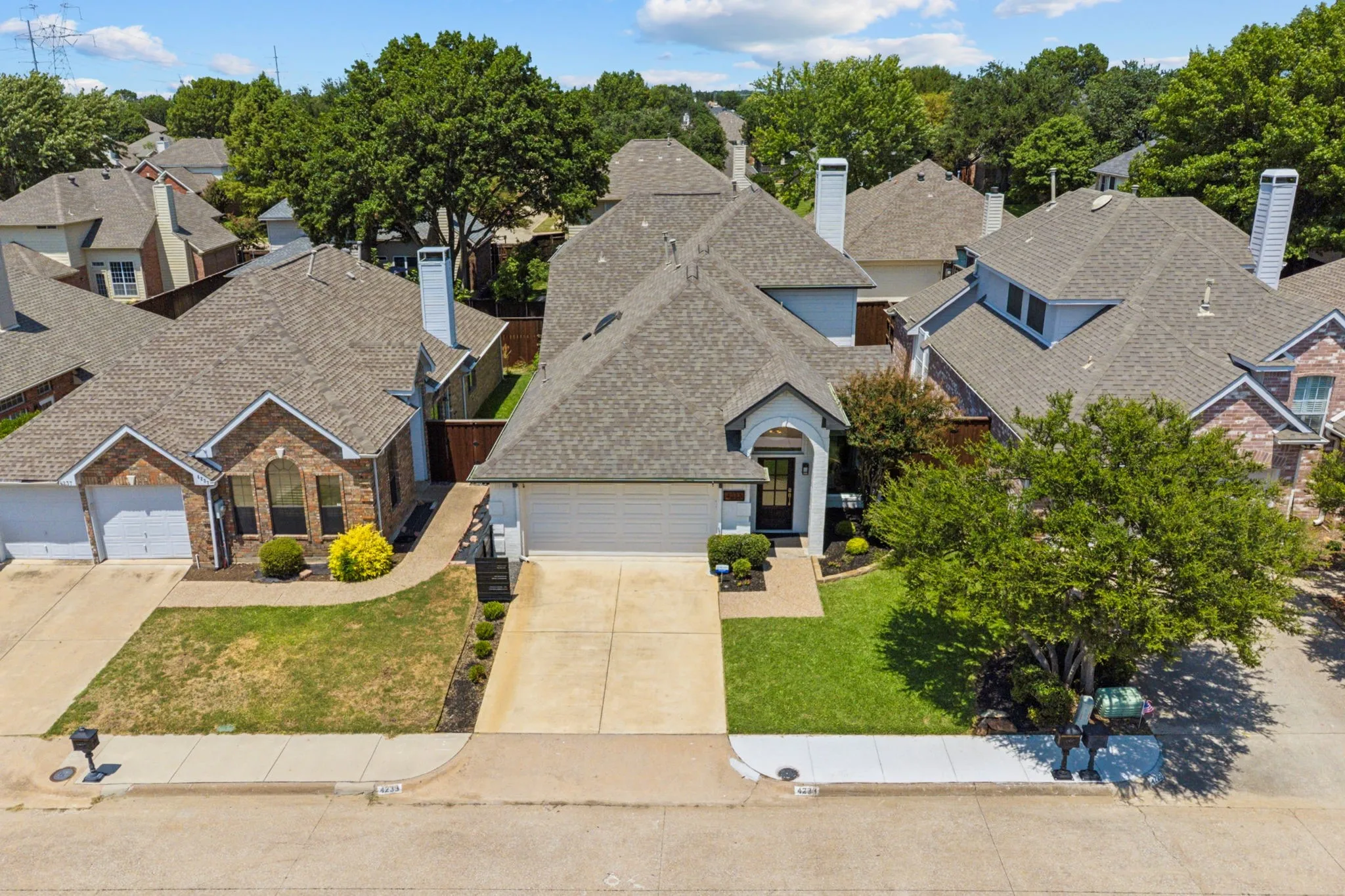 View of front of house featuring driveway, a front yard, a residential view, an attached garage, and a shingled roof