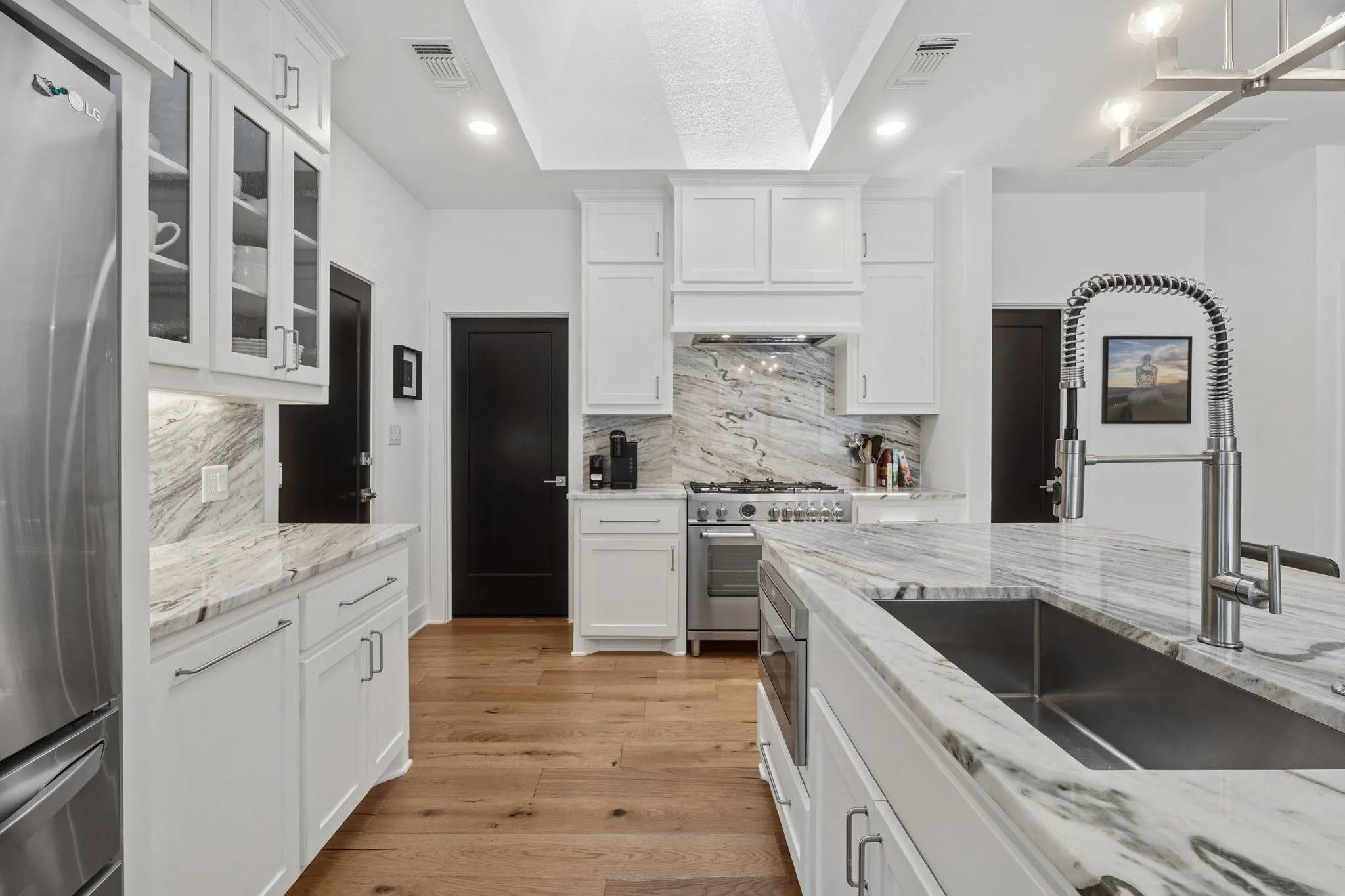 Kitchen featuring appliances with stainless steel finishes, light wood finished floors, white cabinets, and recessed lighting