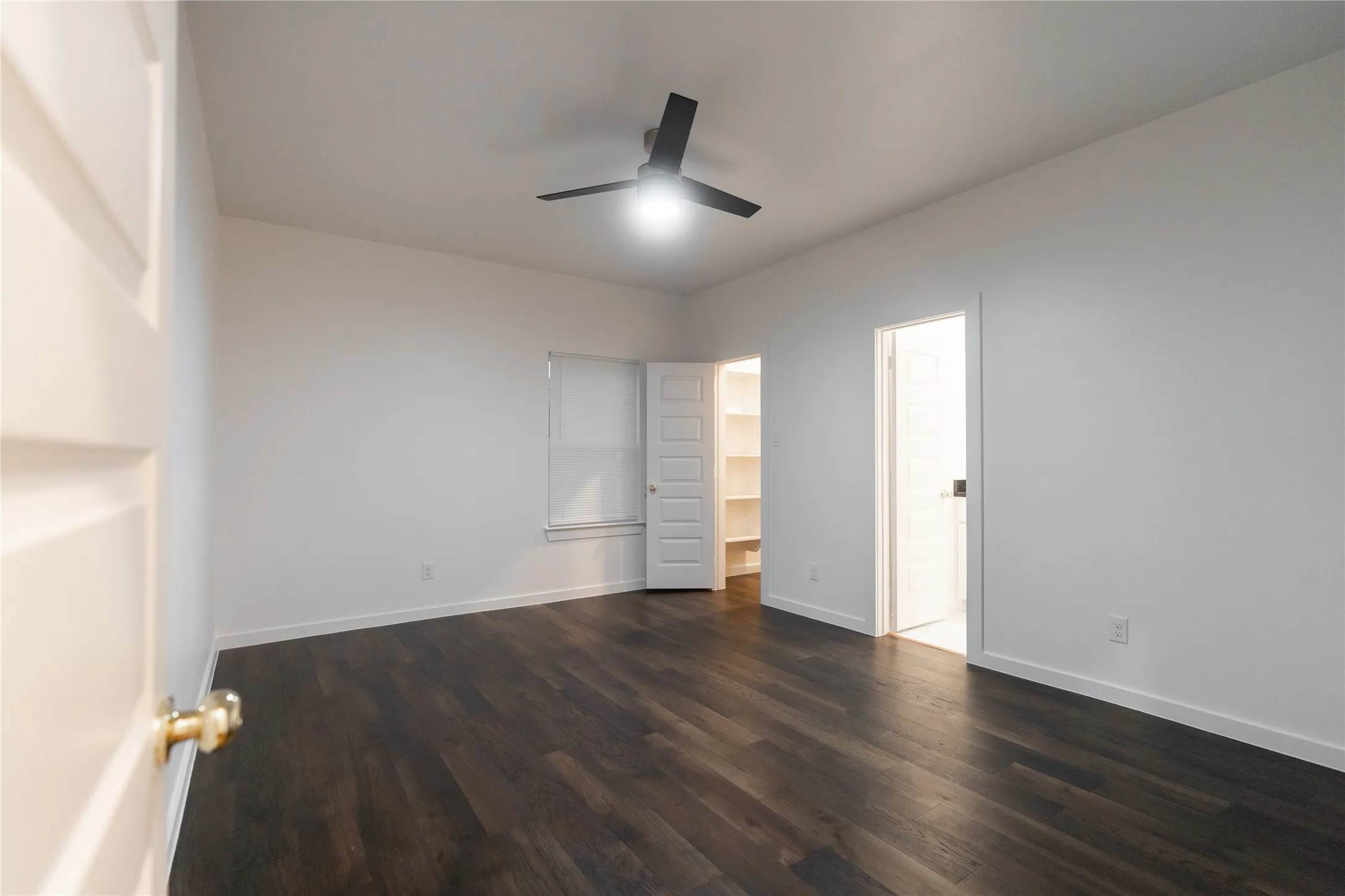 Unfurnished bedroom featuring baseboards, ceiling fan, and dark wood-type flooring