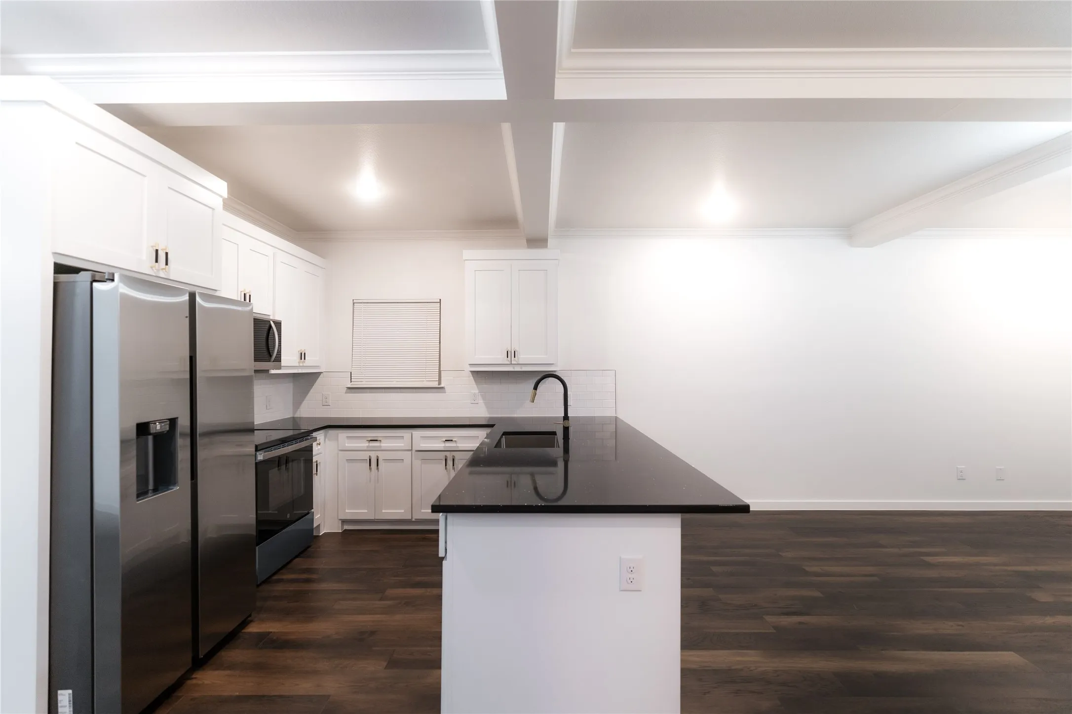 Kitchen with dark wood-style floors, a sink, stainless steel appliances, a peninsula, and dark countertops