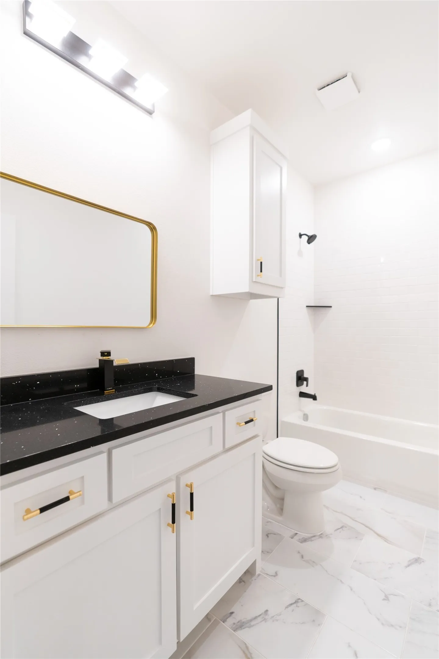 Bathroom with washtub / shower combination, marble finish floor, toilet, and vanity