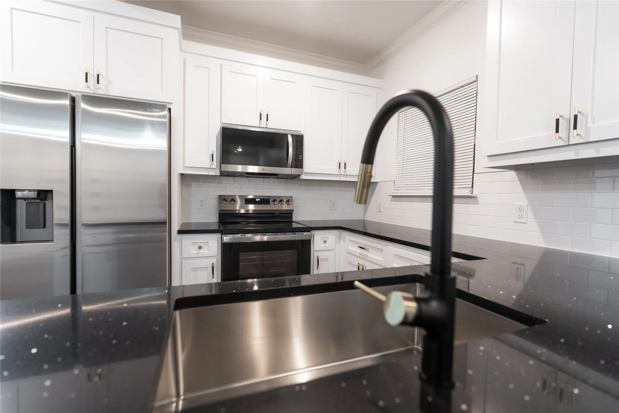 Kitchen with appliances with stainless steel finishes, dark countertops, crown molding, and backsplash