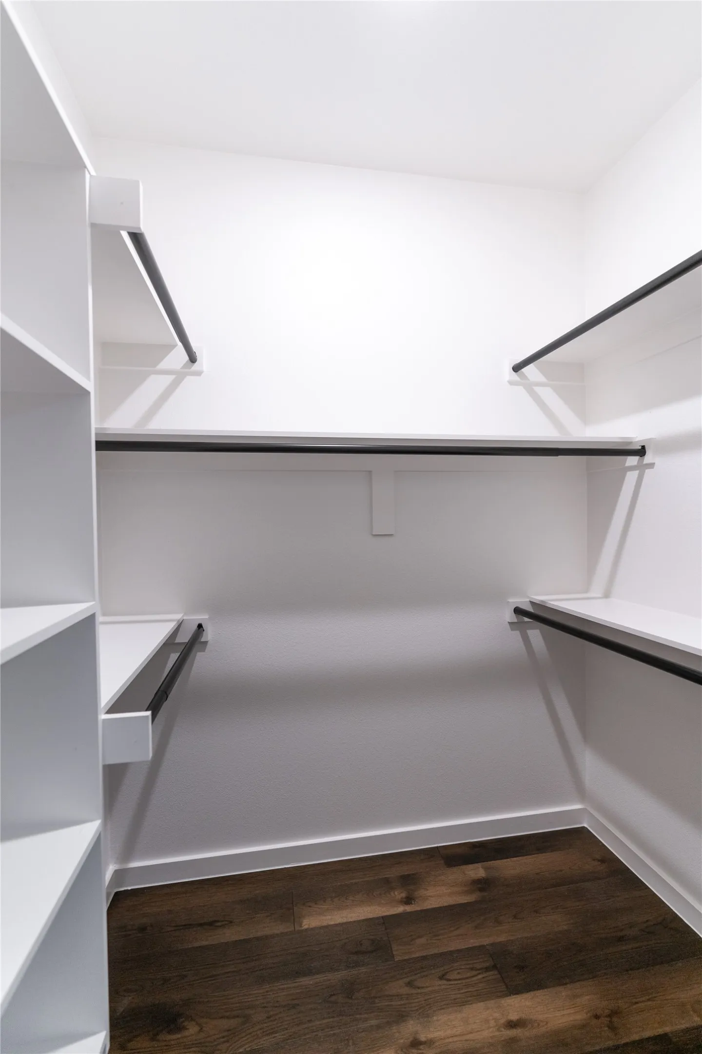 Walk in closet with dark wood-style floors