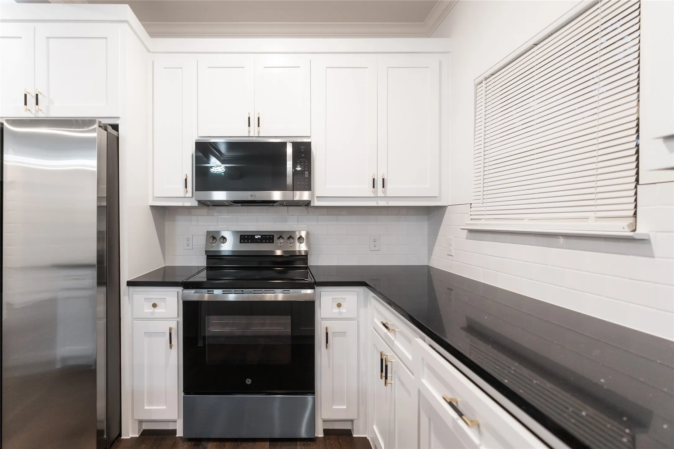 Kitchen with appliances with stainless steel finishes, dark countertops, and white cabinets