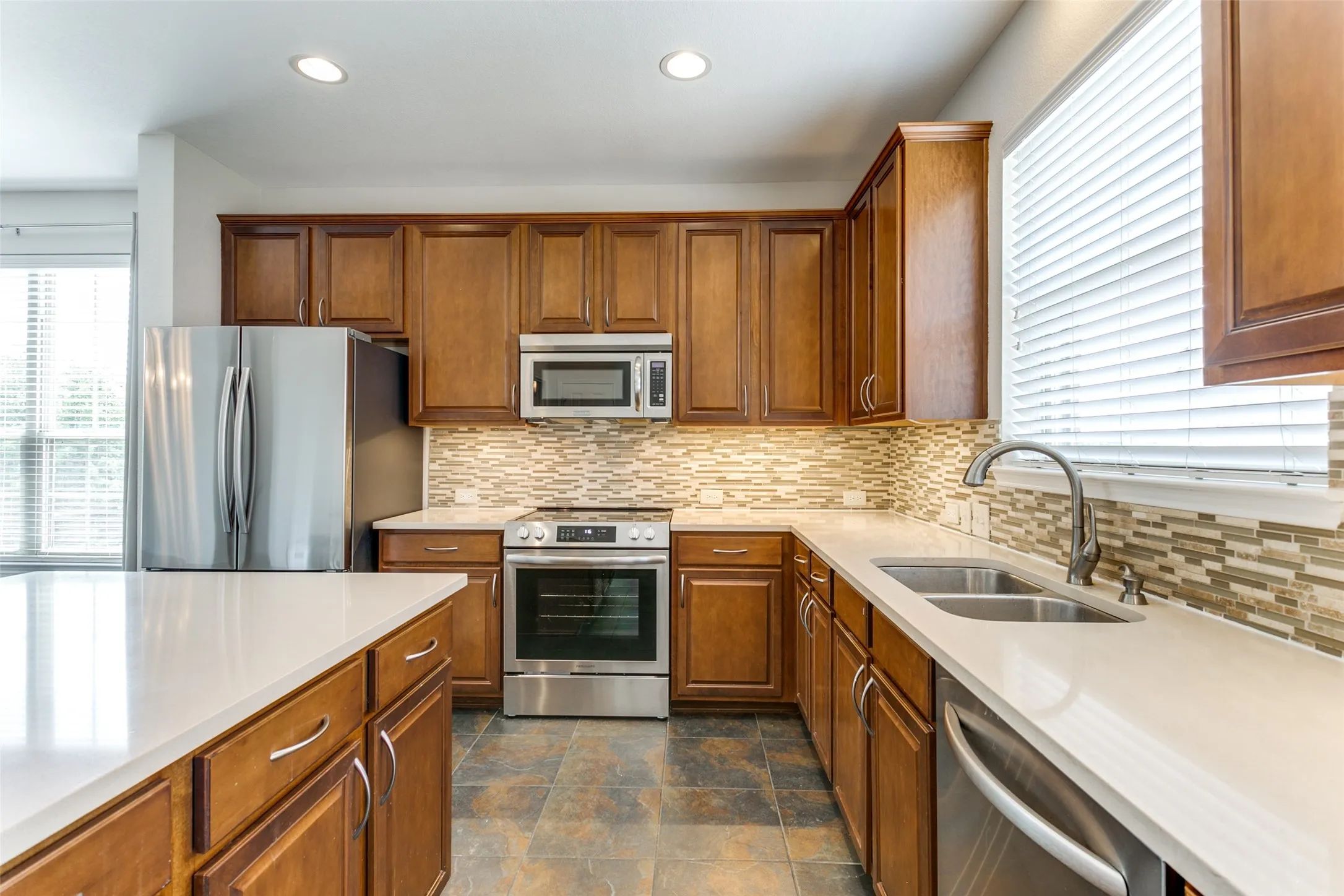 Kitchen with brown cabinets, stainless steel appliances, light countertops
