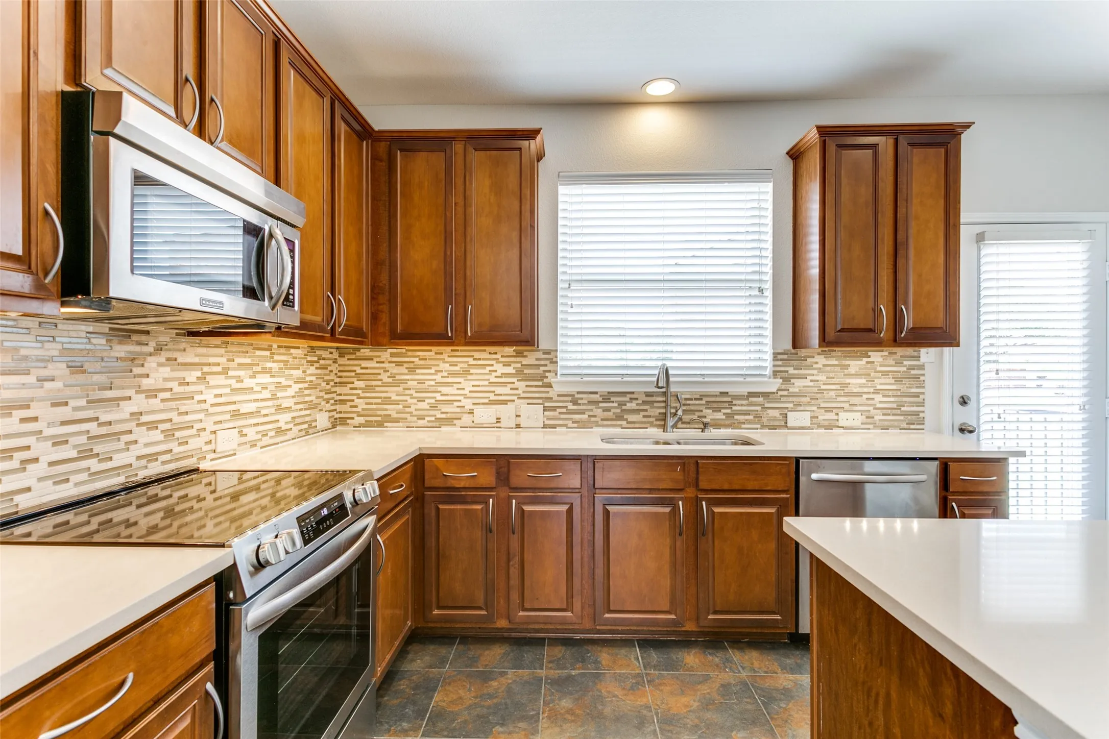 Kitchen with light countertops, a sink, stainless steel appliances, and tasteful backsplash