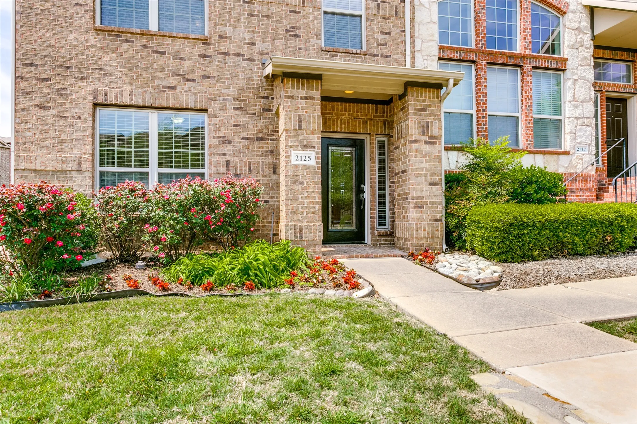Entrance to property with brick siding and a lawn