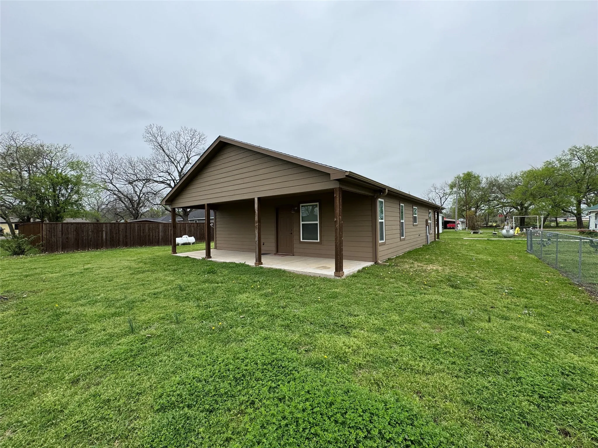 View of property exterior featuring fence, a yard, and a patio area