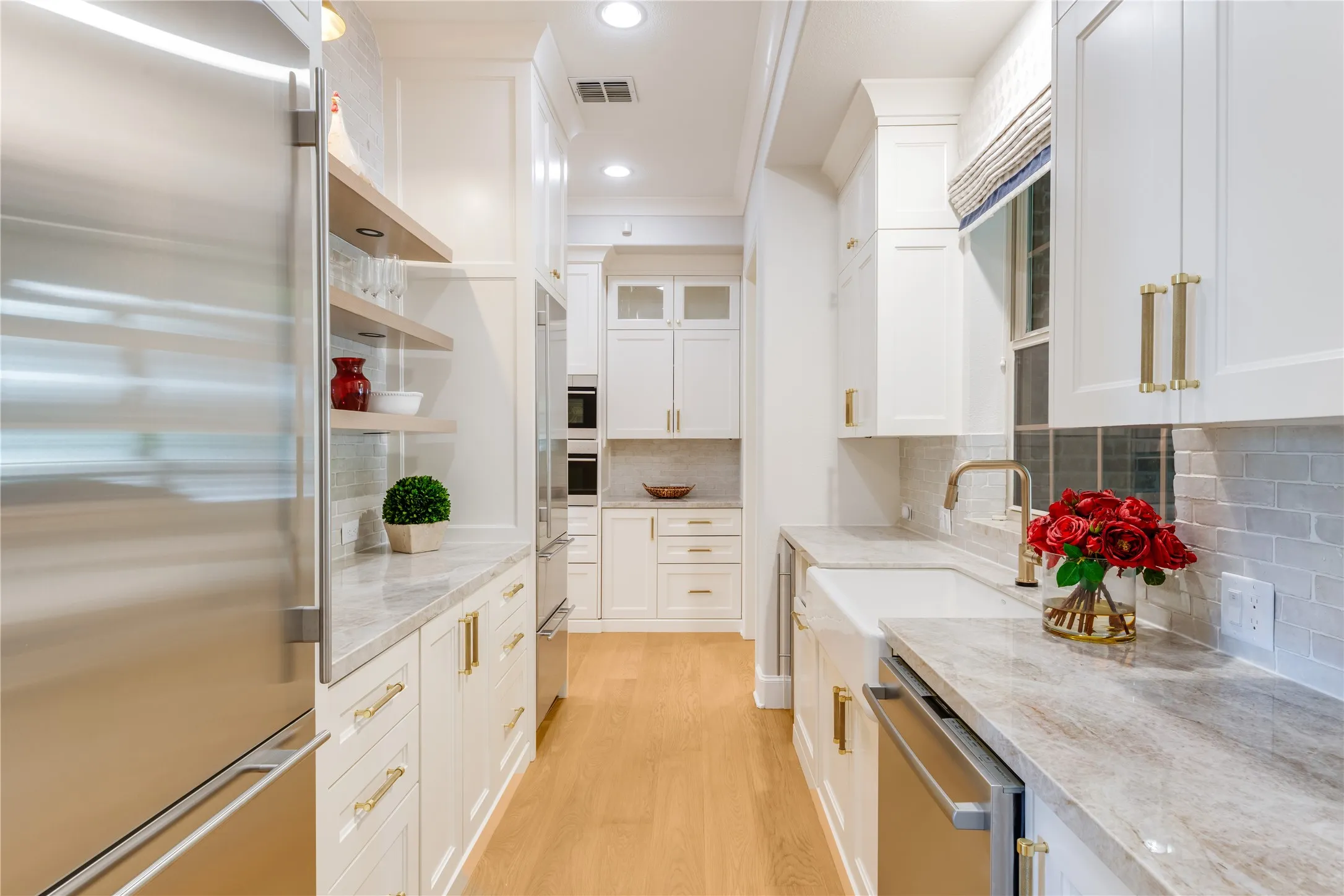 Tucked behind the main kitchen is a fully outfitted prep kitchen. A vast amount of additional storage, a Scotsman pebble ice maker + dual Sub-Zero refrigerator on the right, freezer on the left & a handy second farm sink with views to the raised garden beds in the side courtyard.  To the far right....an extra large utility room with even more cabinet storage & utility sink.