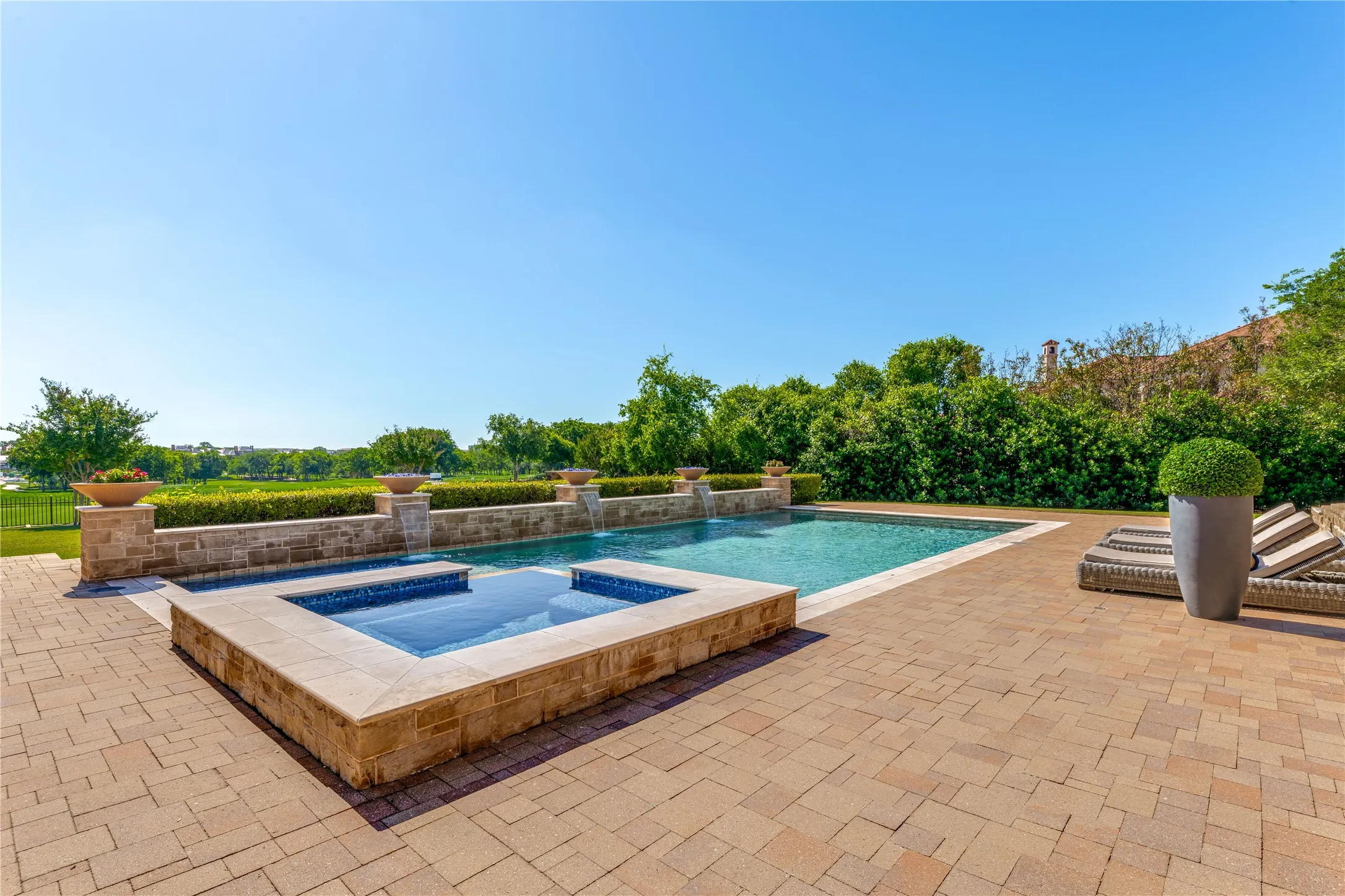 The swimming pool is a true resort-style retreat, designed to dazzle both day & night. Accented natural gas fire bowls, flower bowls & waterfall features, the lap pool has a shallow entry splash pad/tanning ledge to lounge on. Automated controls offer an array of pool light colors for a glimmering setting after sunset. The elevated spa is generously sized for quiet evenings & lively gatherings.