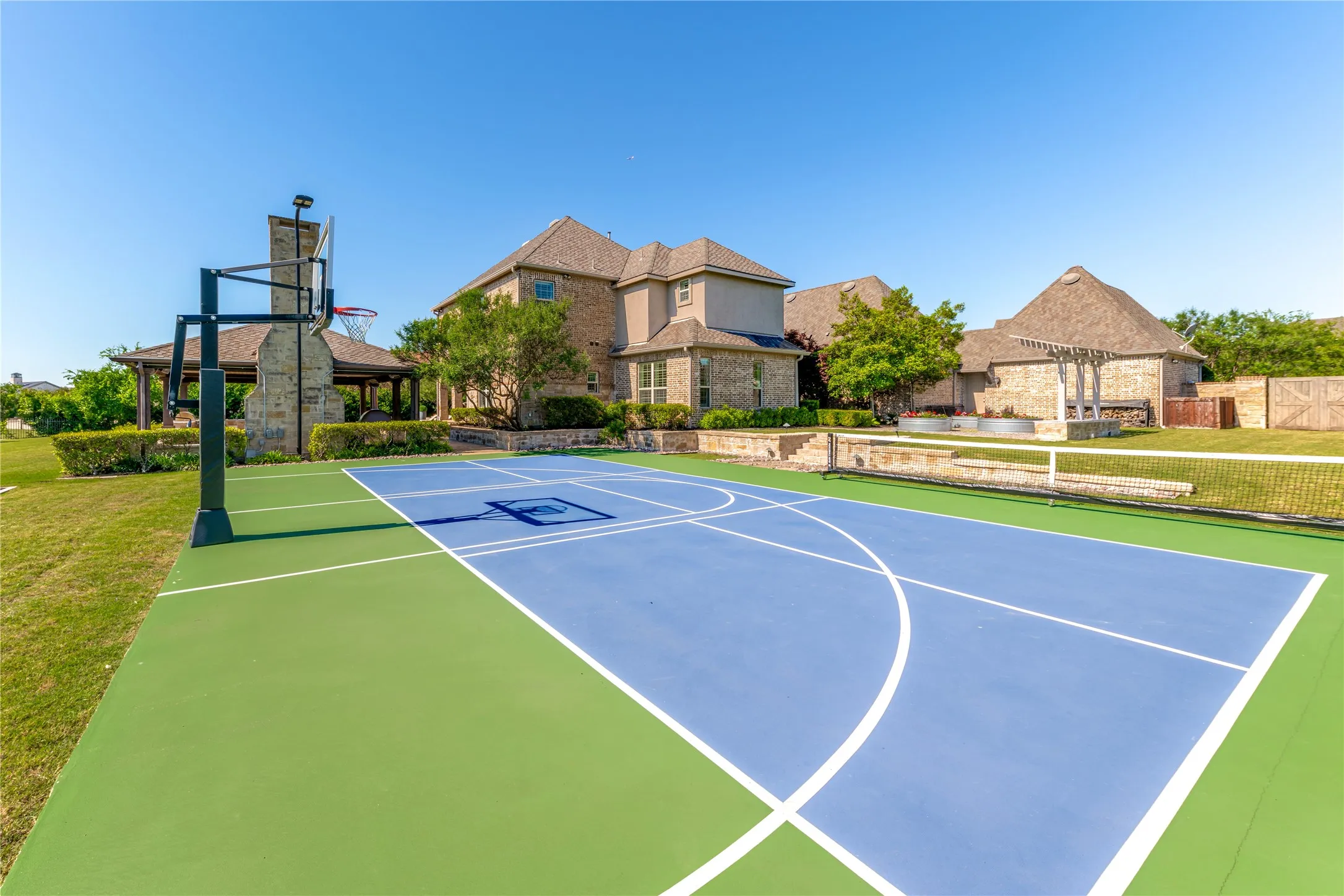 The sport court is a high-energy hub for both basketball & pickleball enthusiasts. Note the fully textured surface with lines for both sports, an adjustable height basketball hoop & the portable pickleball net. Game on!