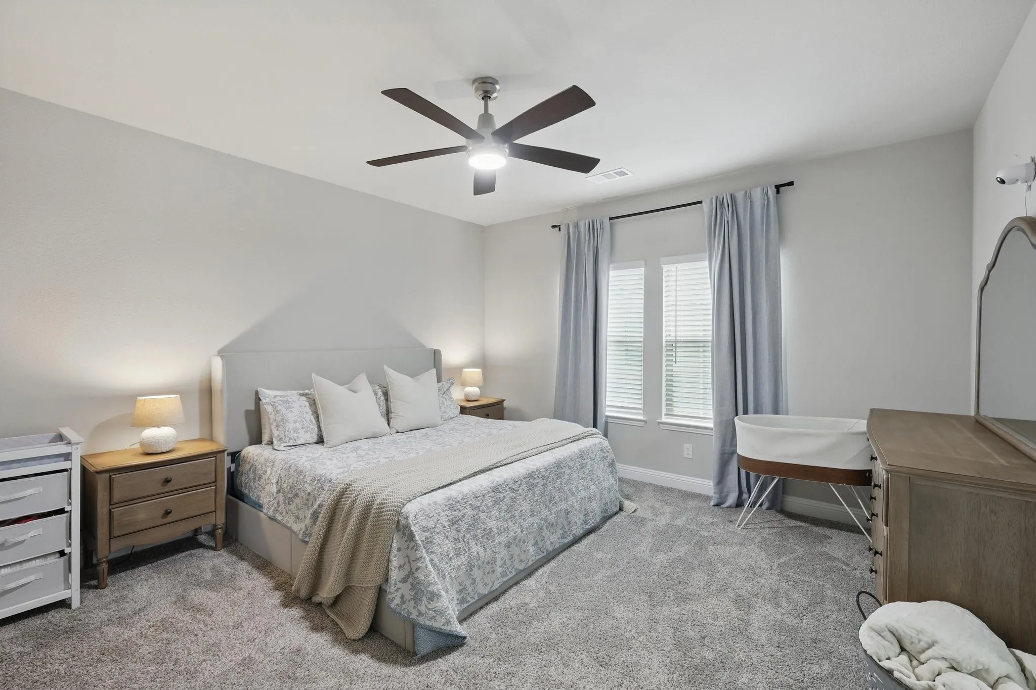 Bedroom featuring baseboards, light carpet, visible vents, and a ceiling fan