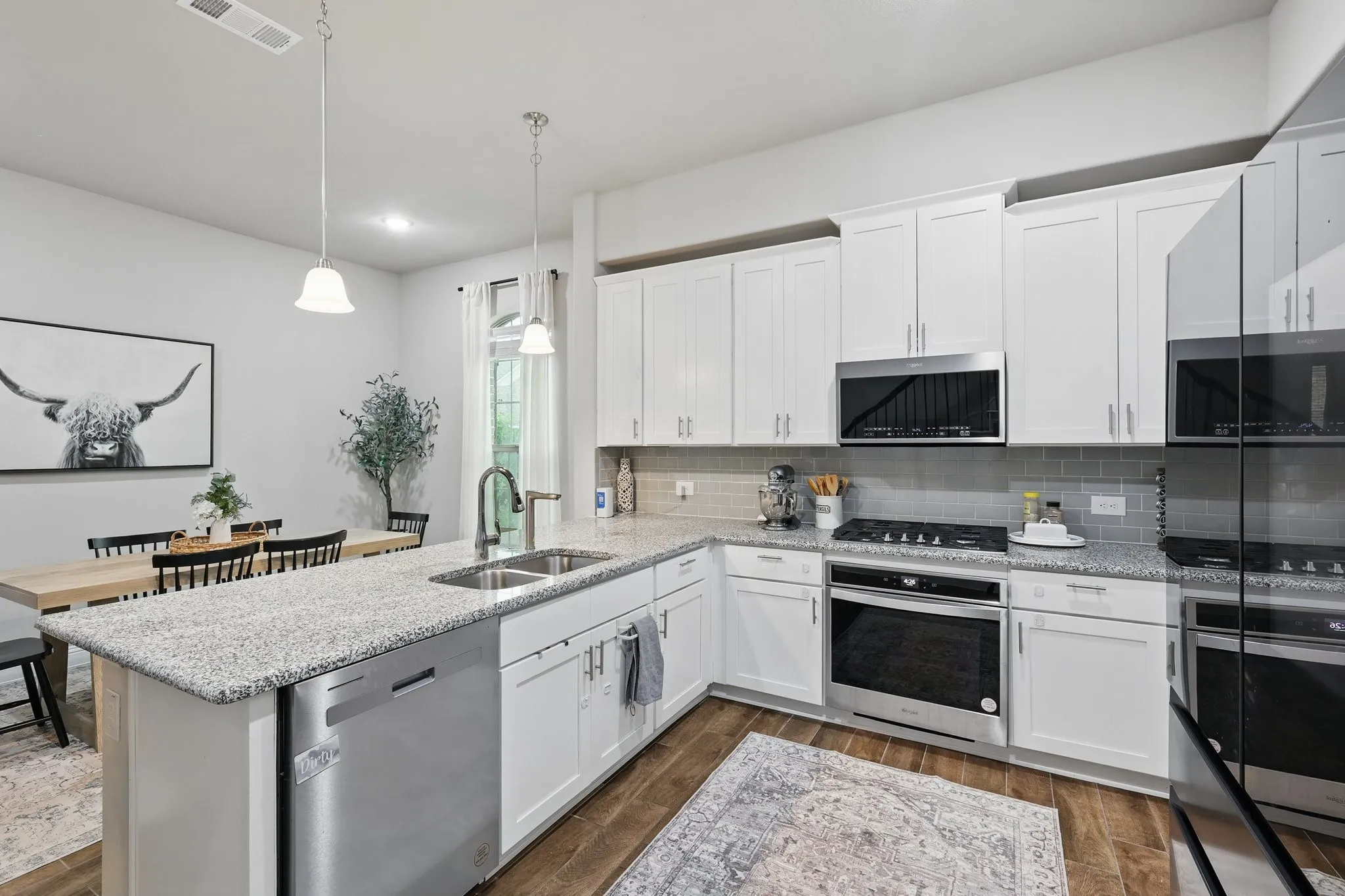 Kitchen featuring a sink, a peninsula, visible vents, backsplash, and appliances with stainless steel finishes