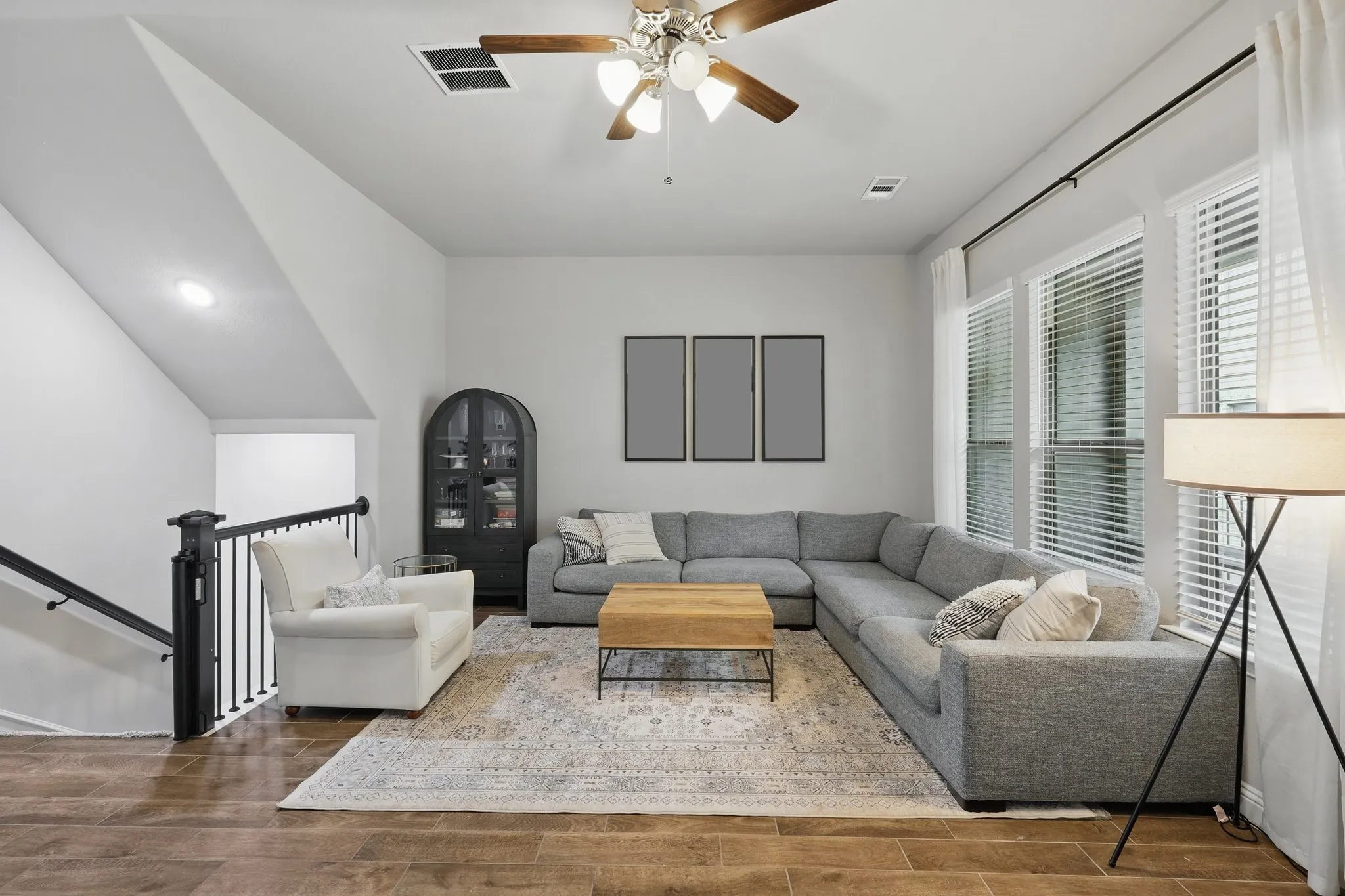 Living area with visible vents, wood finished floors, and ceiling fan