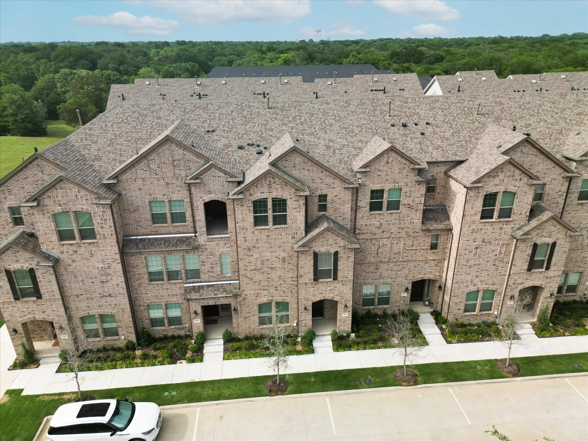 View of front facade with uncovered parking and brick siding