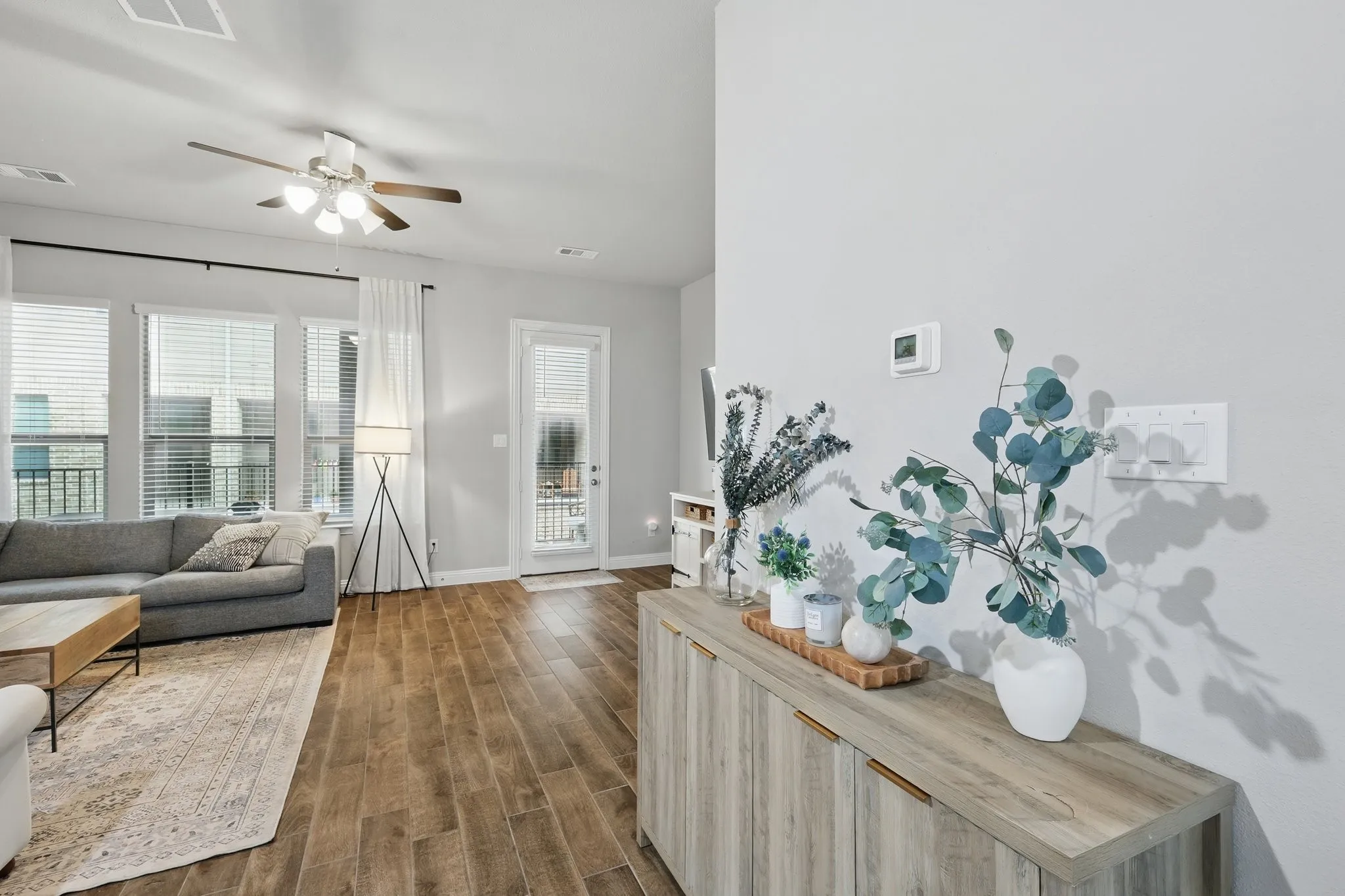 Living room with dark wood finished floors, visible vents, baseboards, and ceiling fan