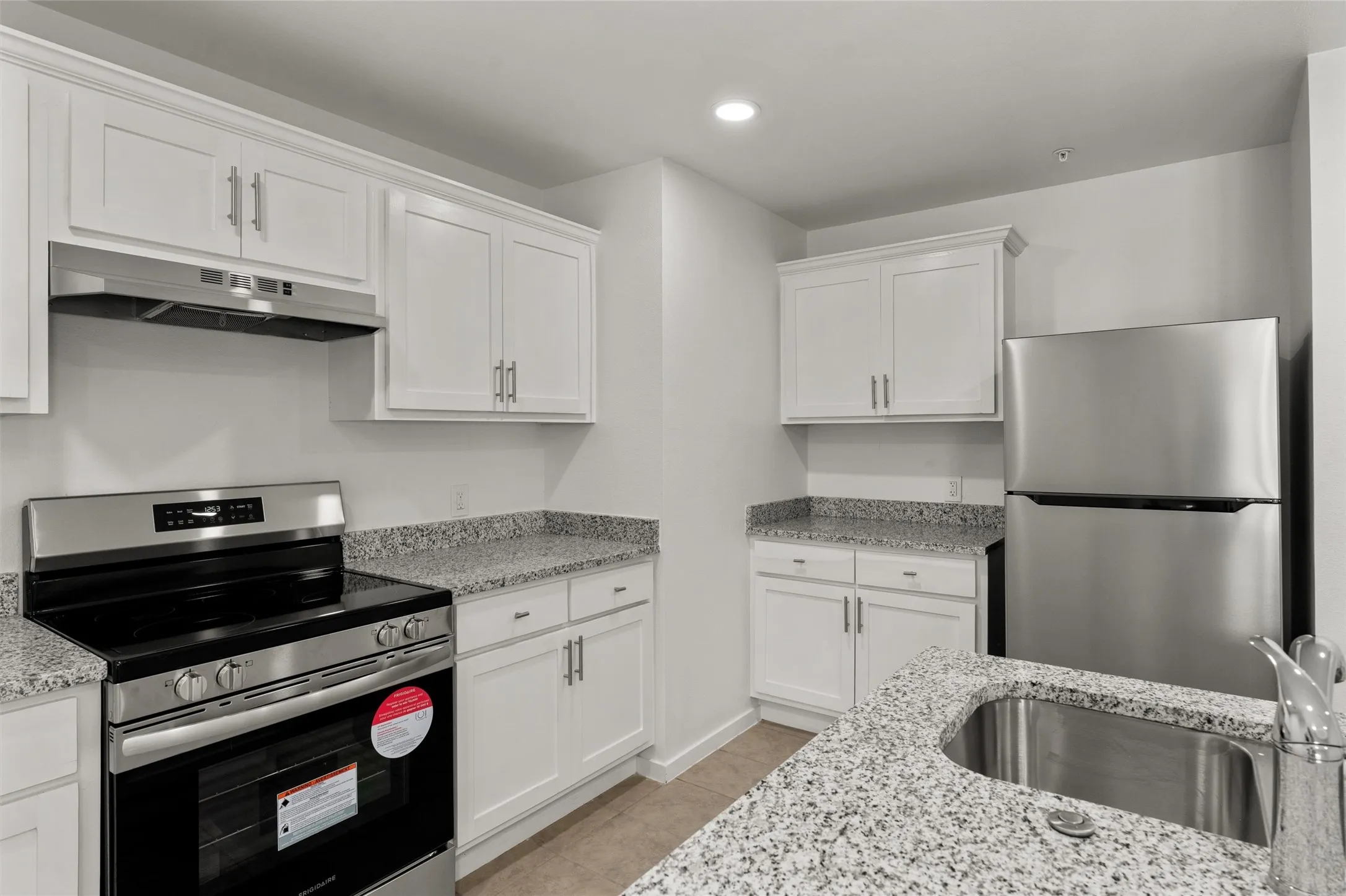 Kitchen featuring a sink, white cabinets, stainless steel appliances, and under cabinet range hood