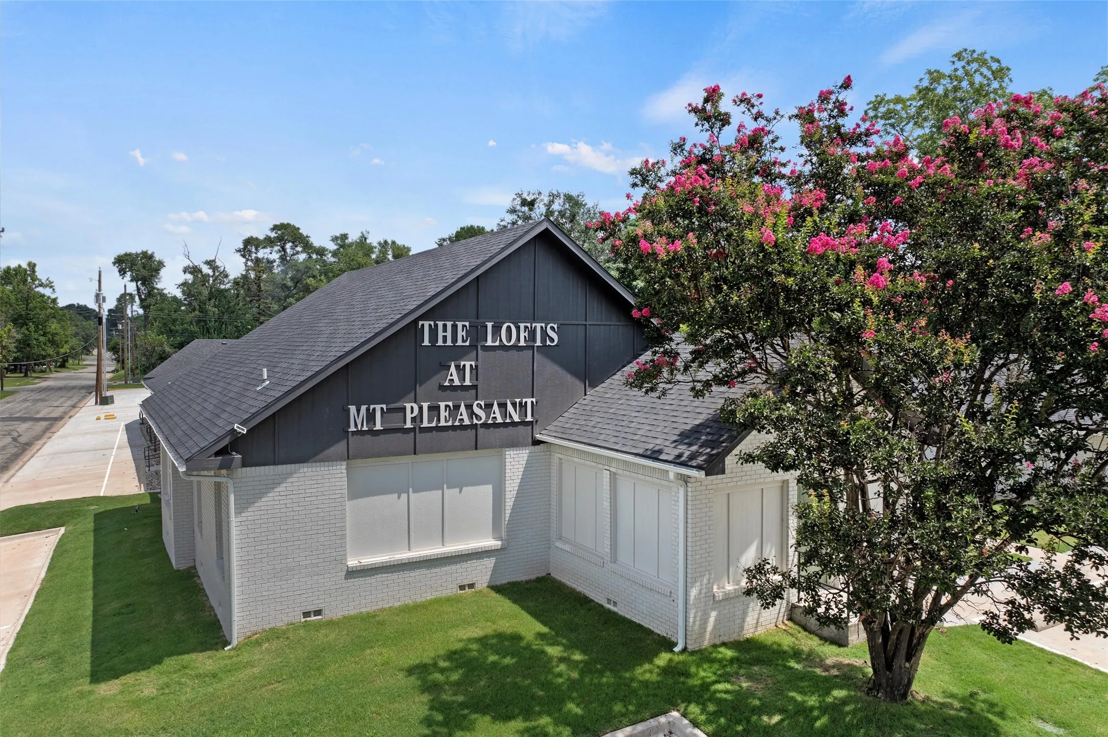 View of side of property with brick siding, a shingled roof, and a lawn