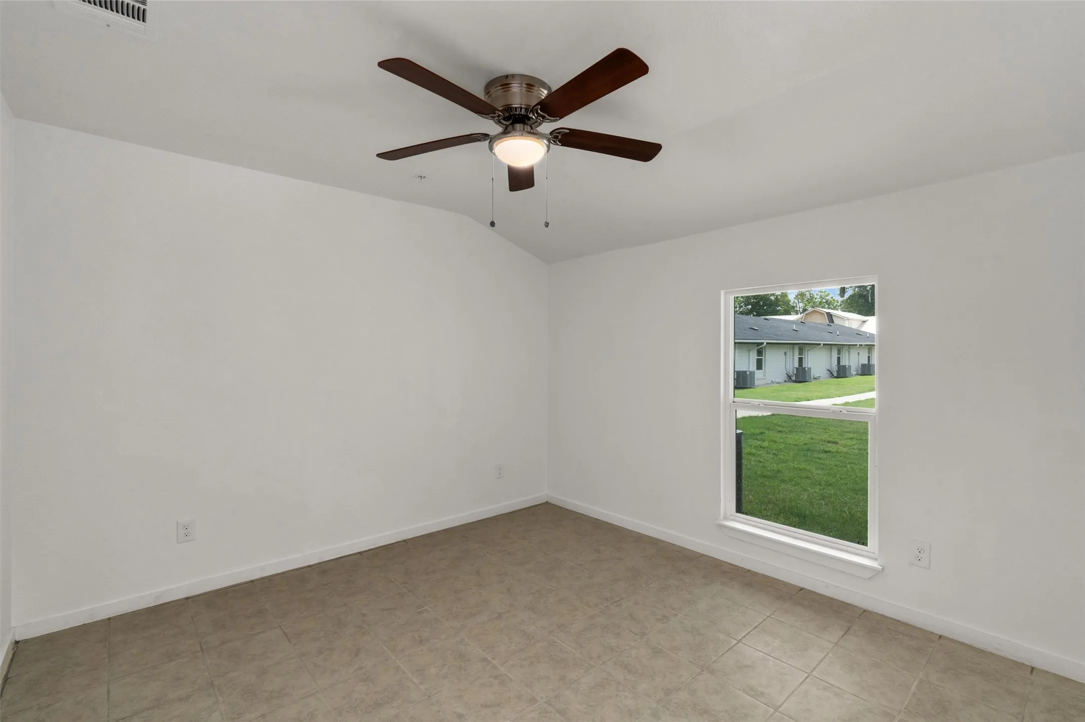 Spare room featuring baseboards, a ceiling fan, vaulted ceiling, and visible vents