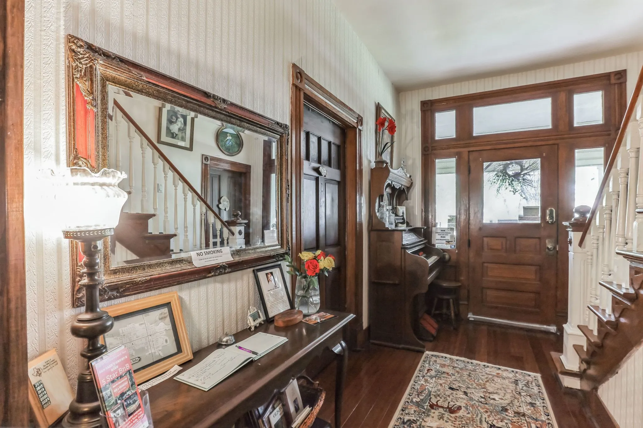 Foyer entrance with stairs, dark wood-style floors, and wallpapered walls