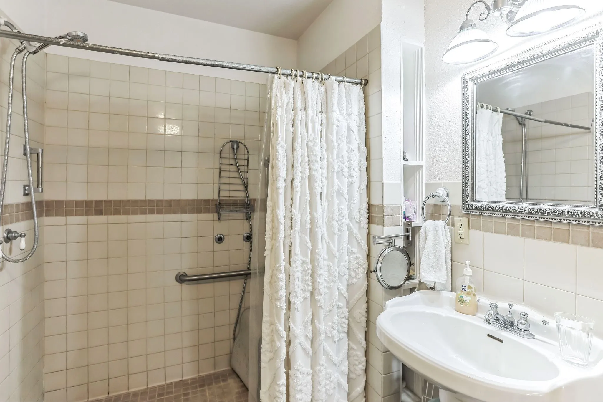Bathroom featuring a shower stall, tasteful backsplash, tile walls, and a sink