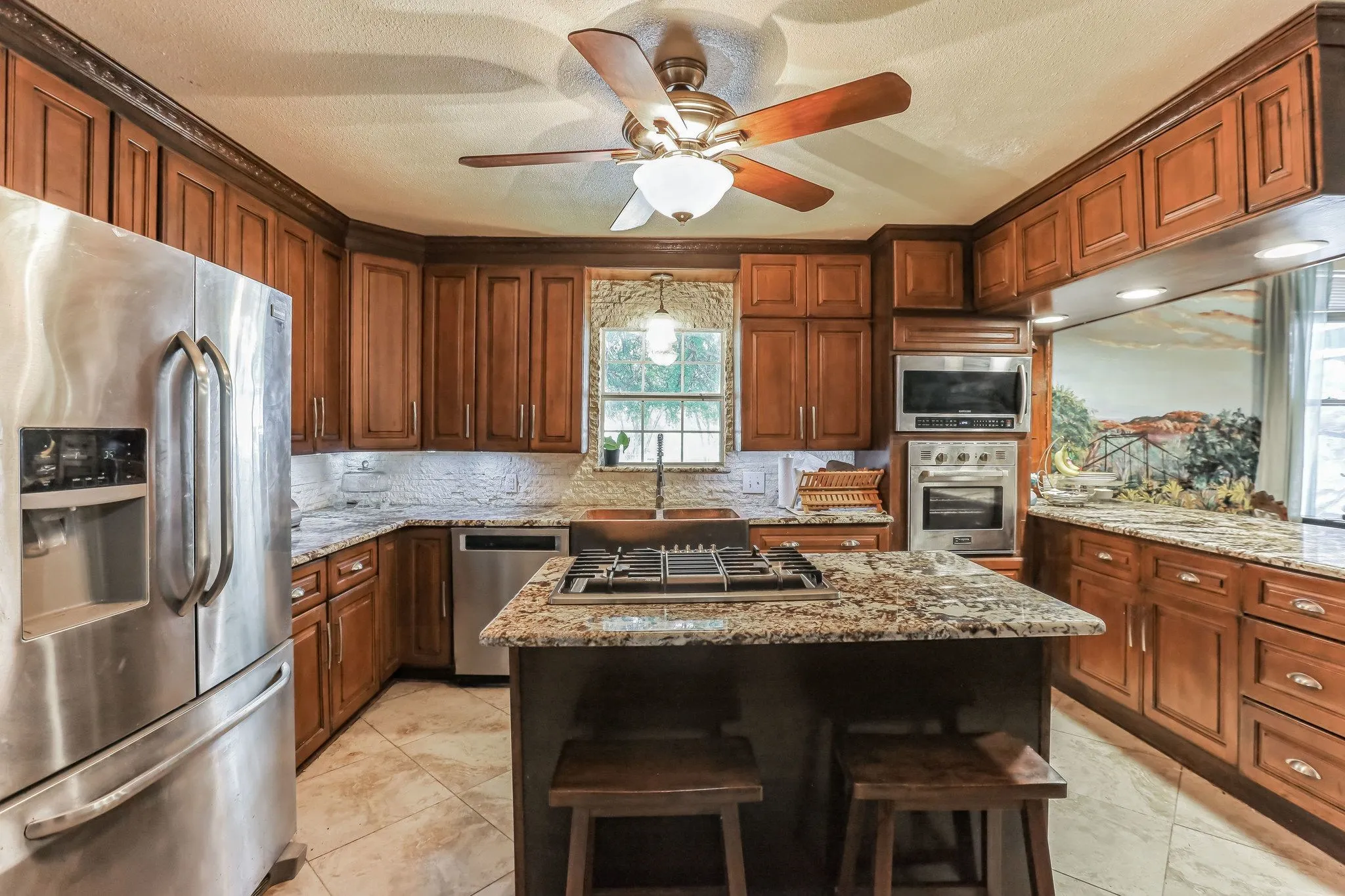 Kitchen featuring a center island, a sink, ceiling fan, appliances with stainless steel finishes, and decorative backsplash