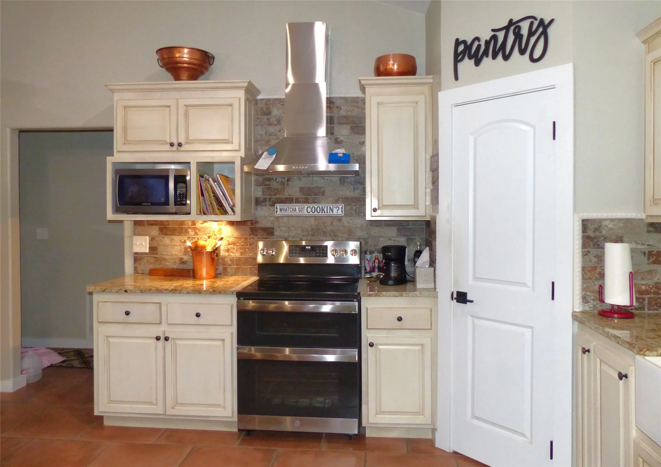 Kitchen with light stone counters, wall chimney exhaust hood, stainless steel appliances, decorative backsplash, and light tile patterned floors
