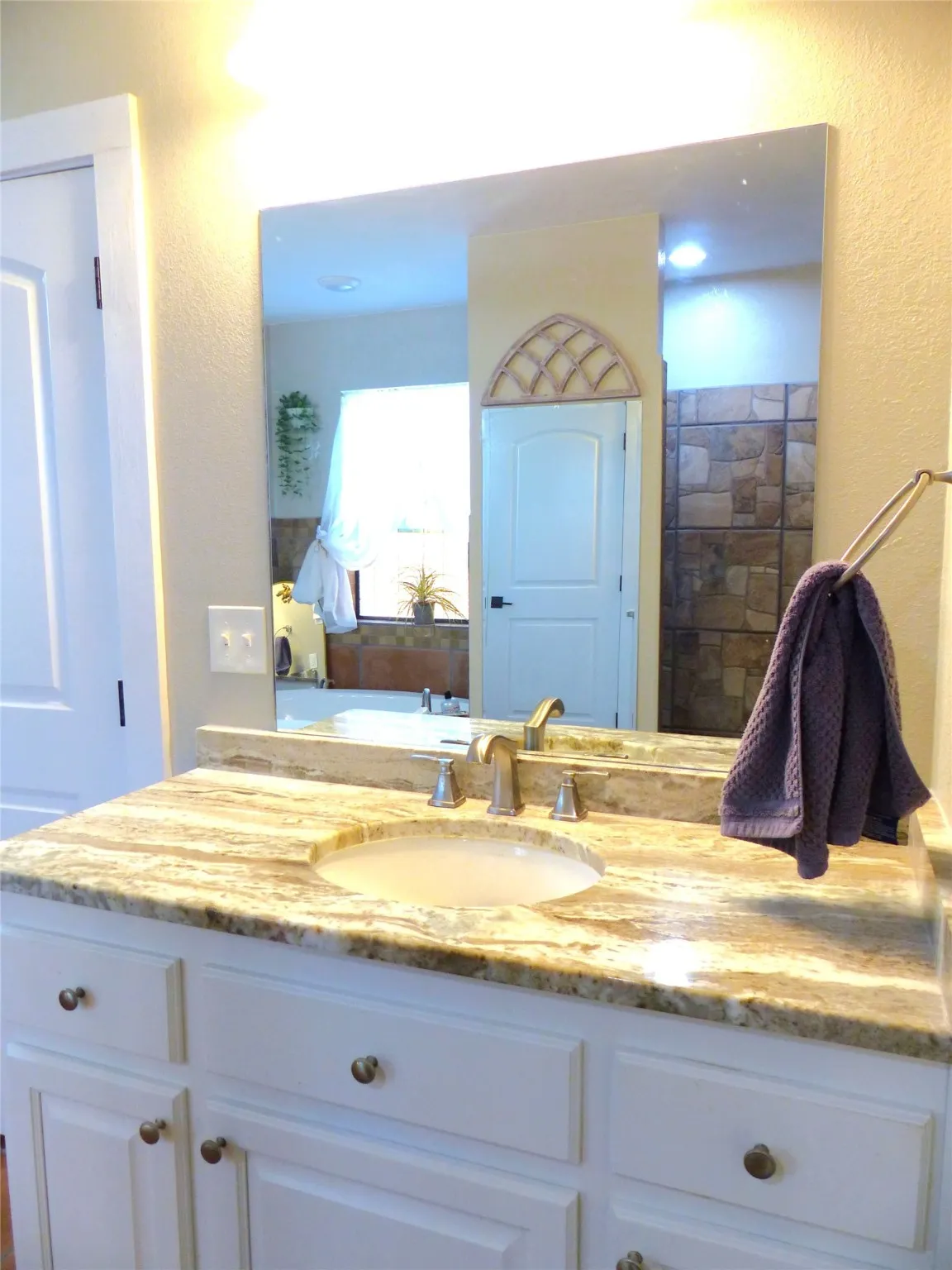 Full bath with vanity and a textured wall